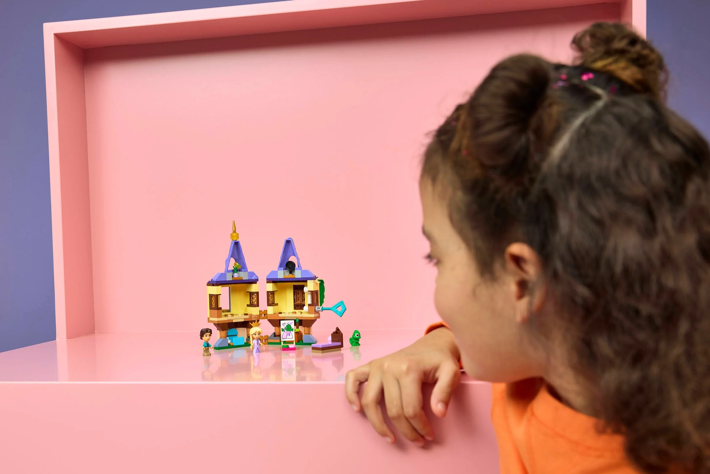 O fetiță se uită la mini turnul Rapunzel, setul 43294. Modelul finalizat, cu minifigurine.