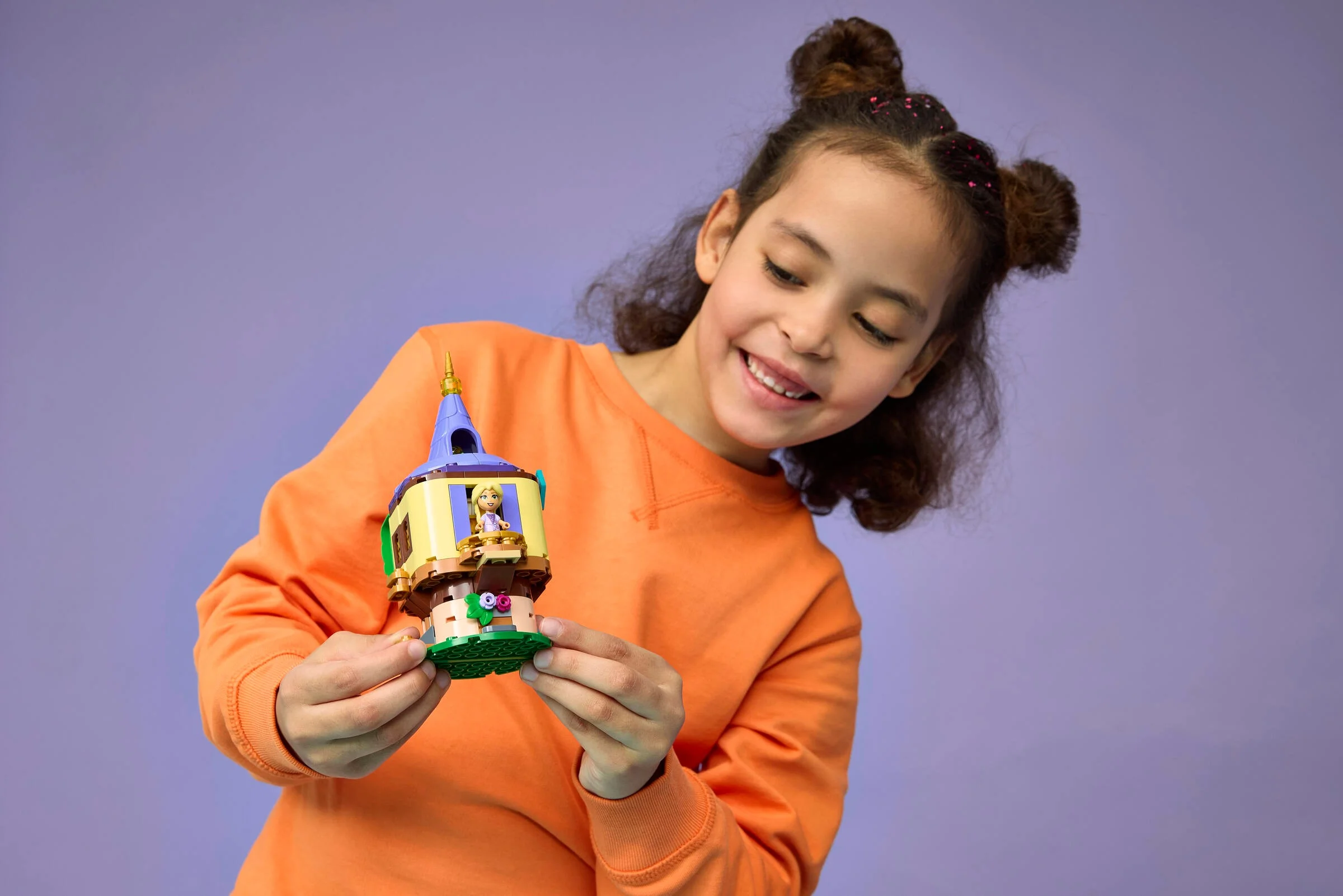 Fetiță zâmbind admirând turnul LEGO Rapunzel, setul 43294. O jucărie încântătoare!