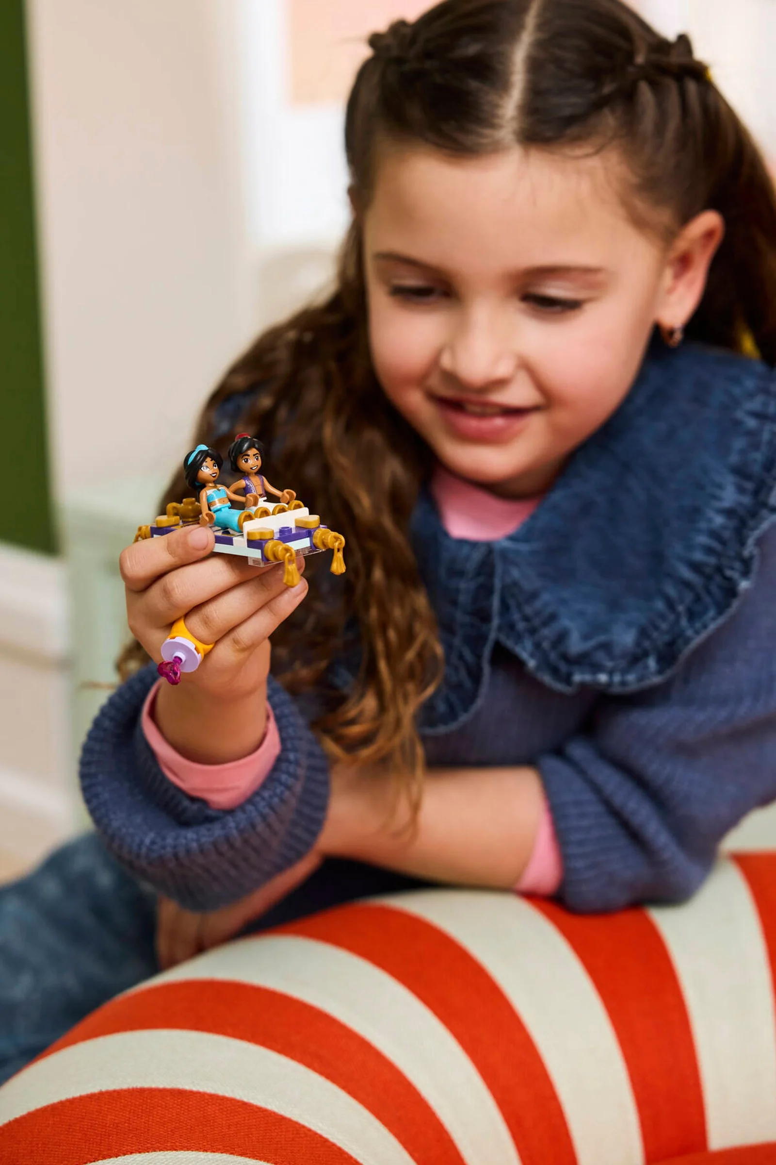 Fetiță admirând covorul zburător LEGO Jasmine. Un inel violet completează setul.