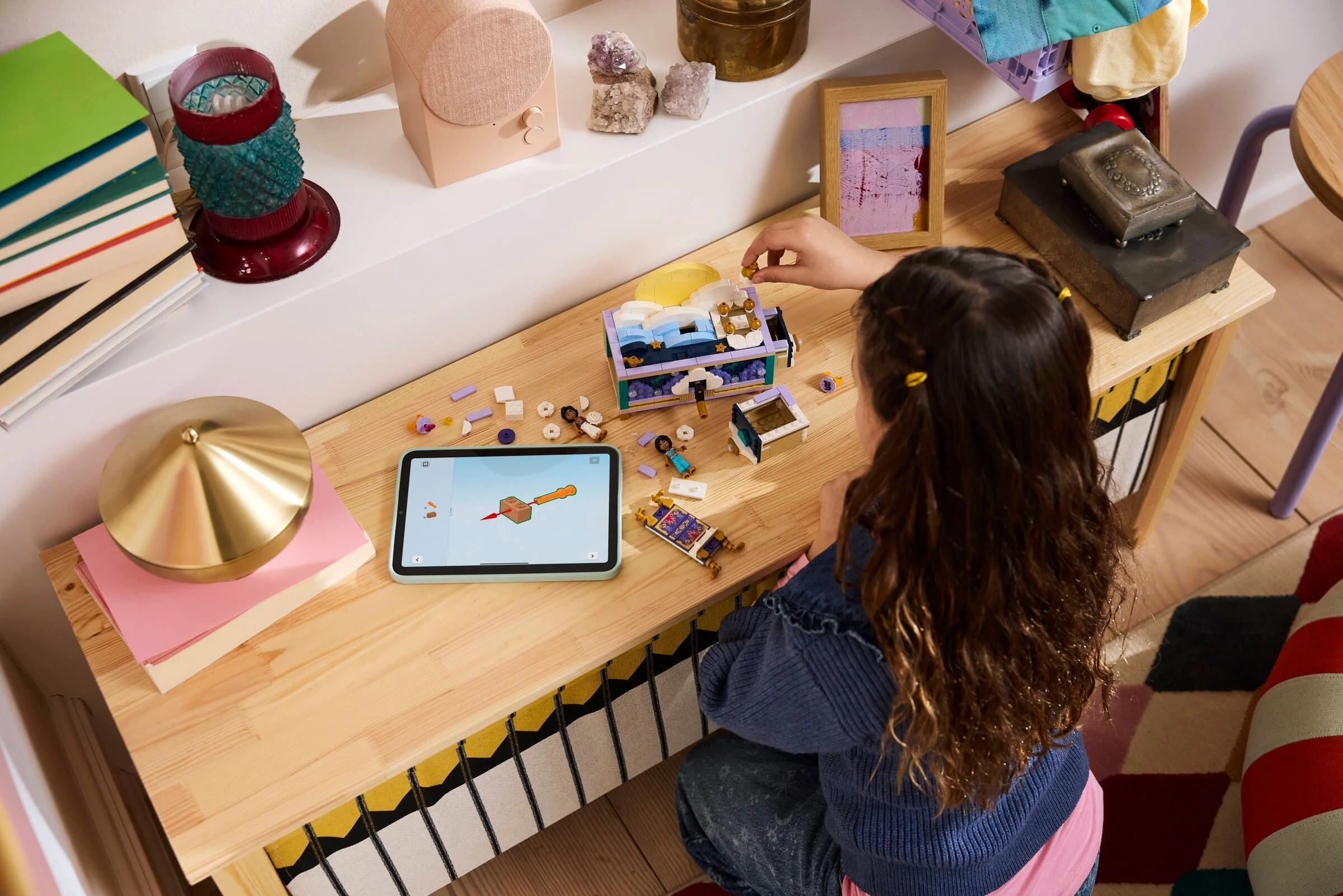 Fetiță construind setul LEGO Cutia cu bijuterii a lui Jasmine (43295) folosind instrucțiuni digitale pe tabletă.