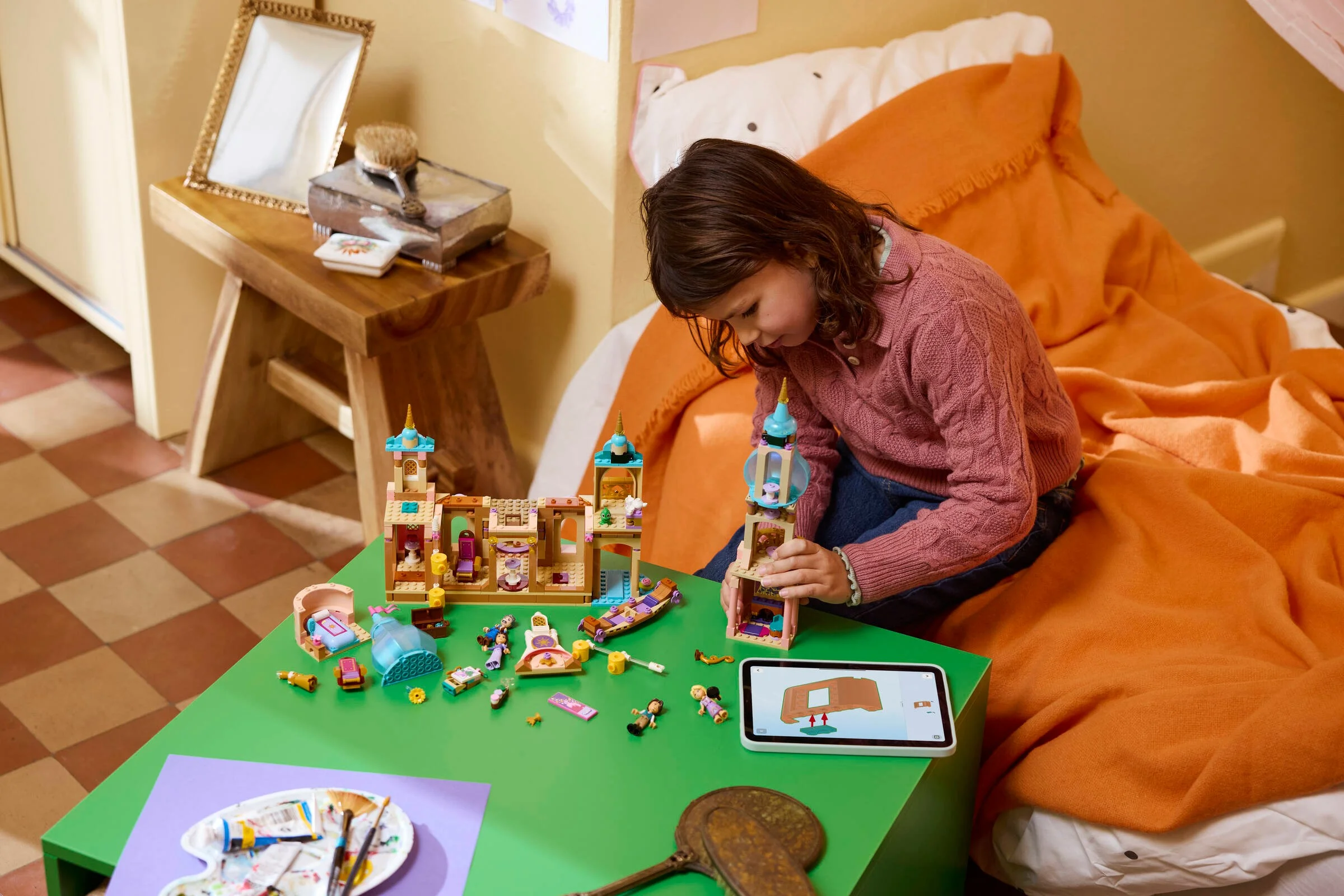 Fetiță construind castelul Rapunzel cu instrucțiuni digitale pe tabletă. Distracție și creativitate!