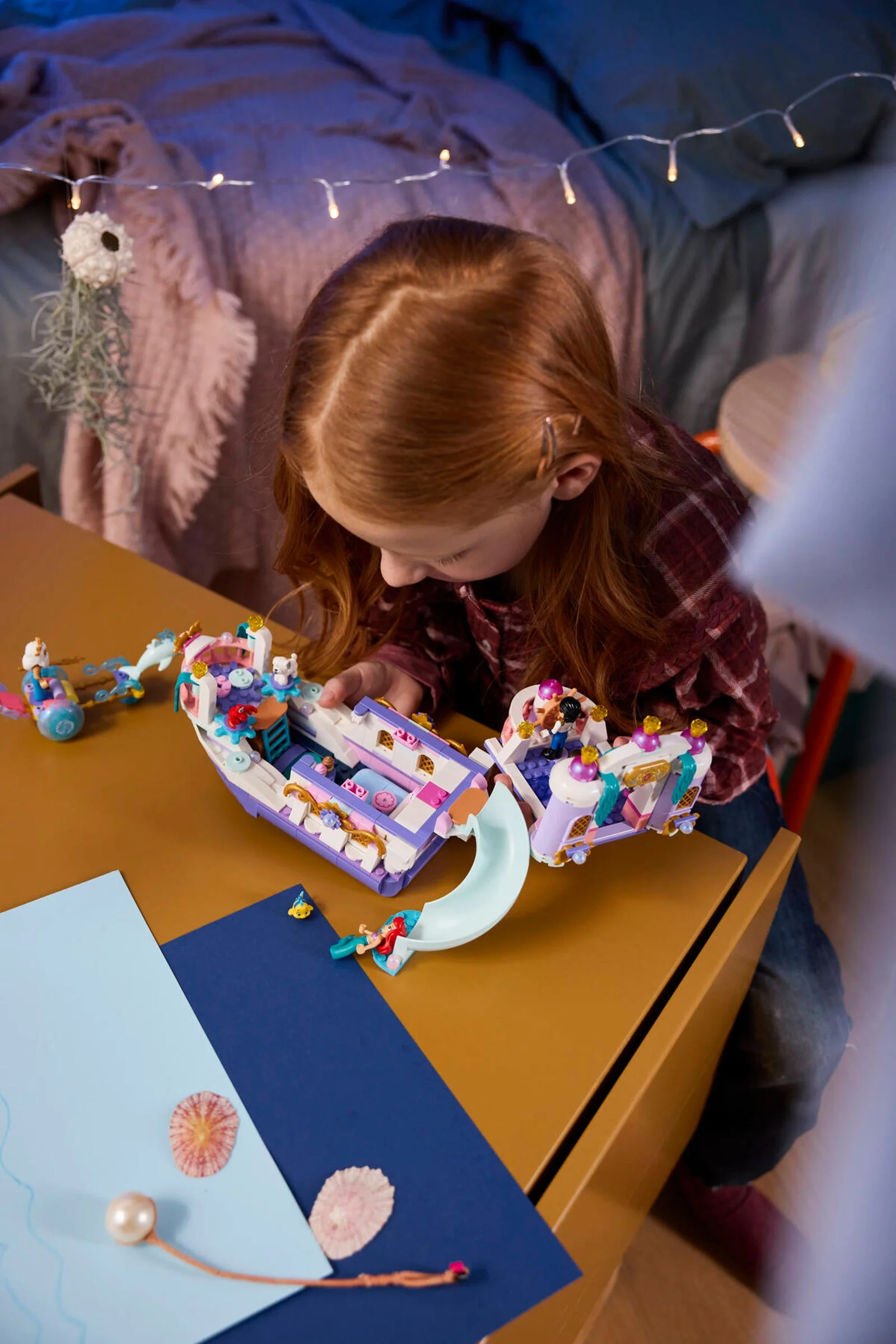 O fetiță se joacă cu setul LEGO Ariel's Royal Wedding Boat. Barcă decorată cu personaje Disney.