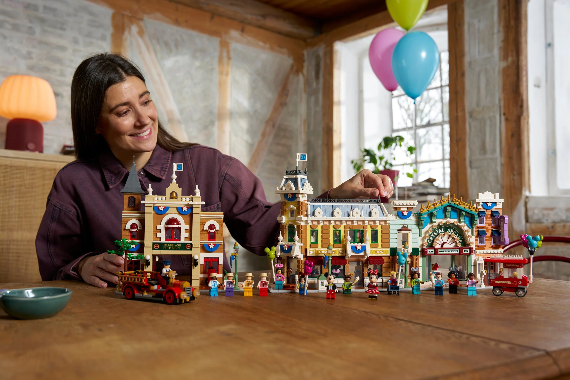 Femeie zâmbind lângă setul LEGO Main Street, U.S.A. (43302), un model detaliat.