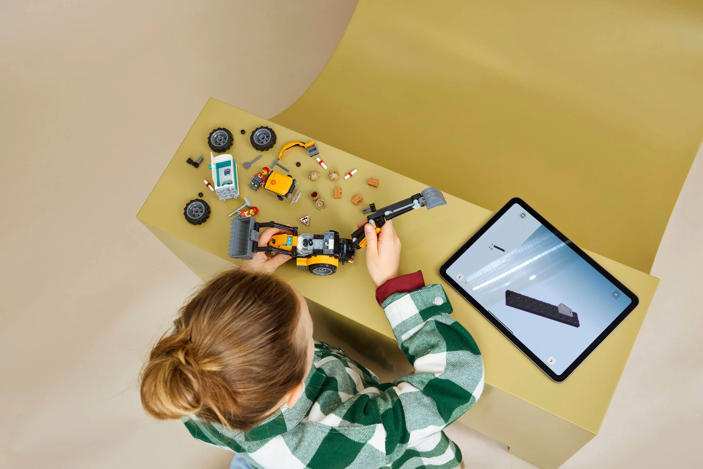 Copil construind încărcătorul frontal LEGO 60480 urmând instrucțiuni digitale pe tabletă.