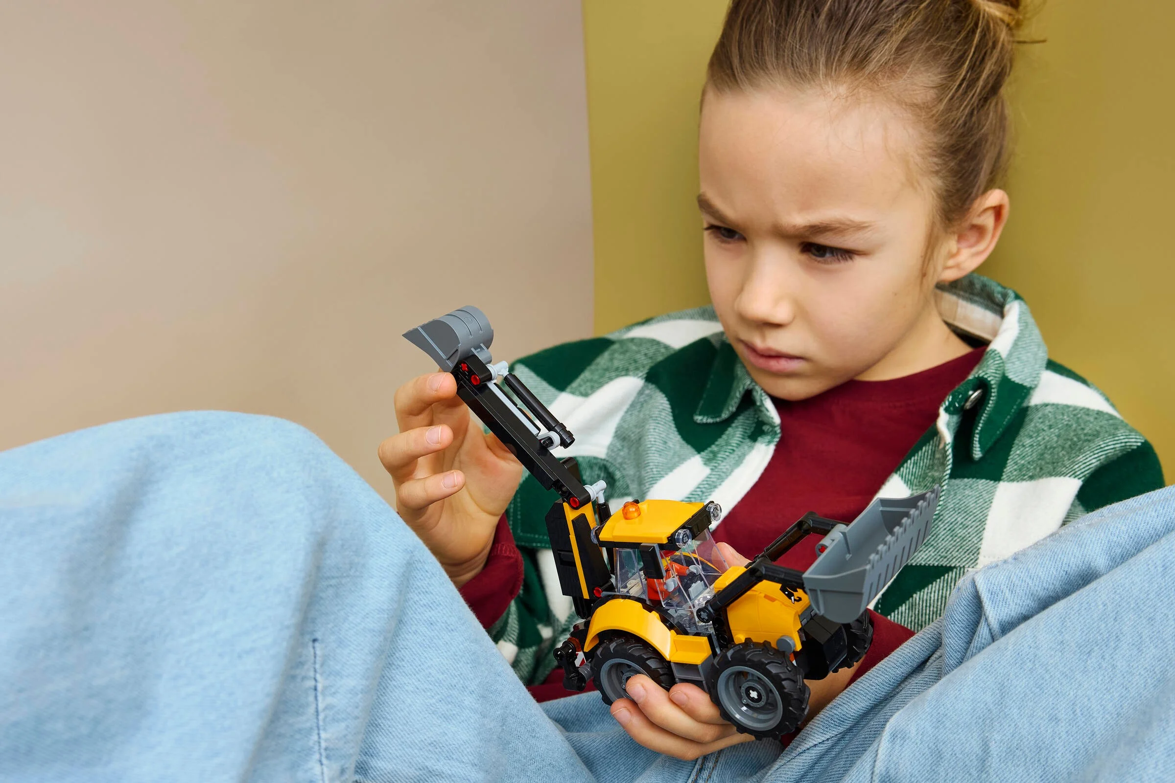 Copil se joacă cu excavatorul LEGO® City 60480, concentrat și curios.