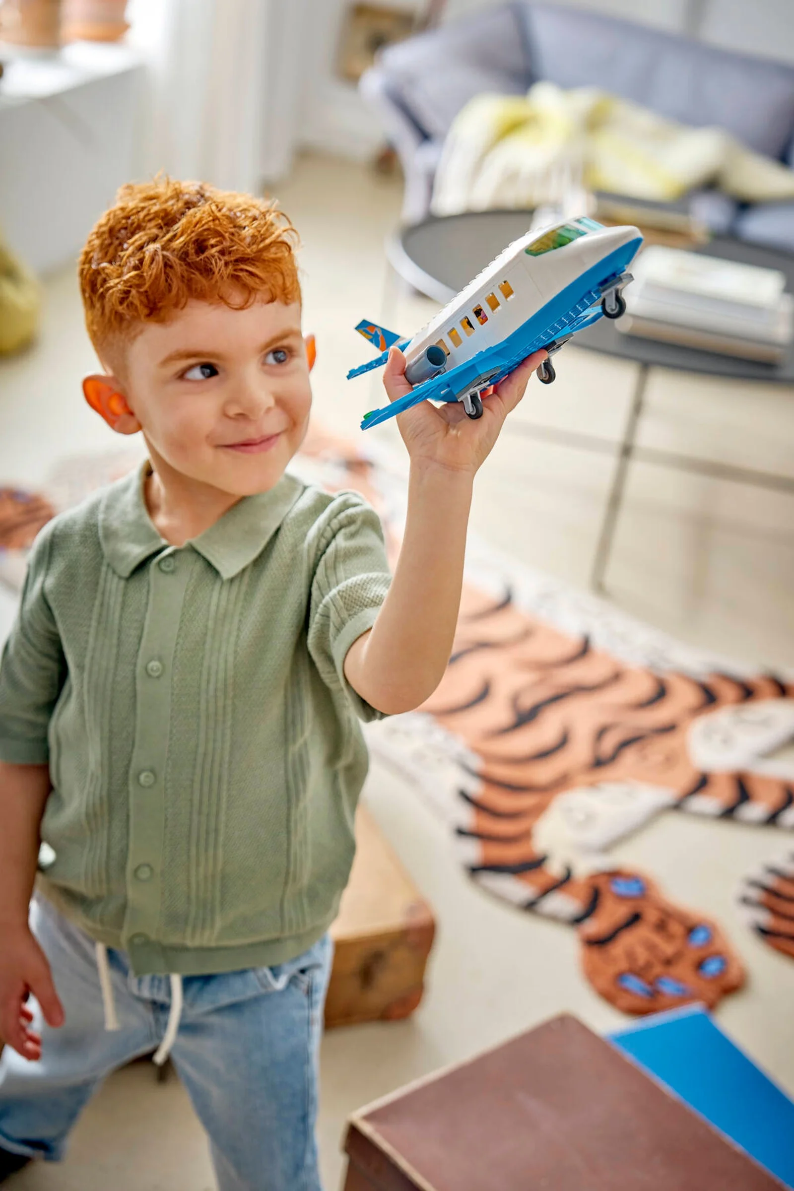 Băiat se joacă cu avionul de pasageri LEGO, zâmbind. Jucărie distractivă și captivantă.