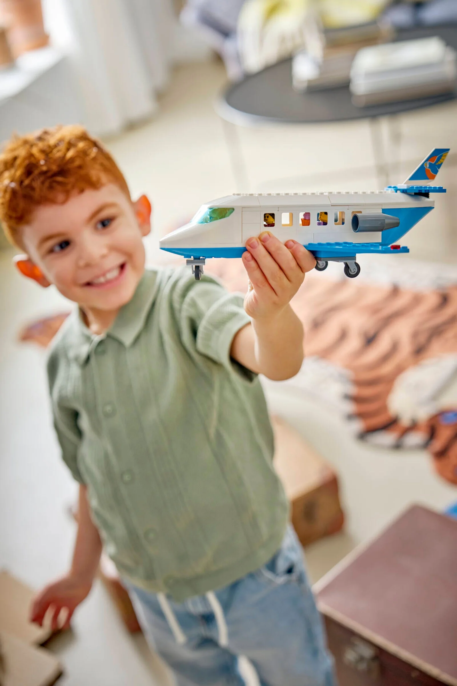 Băiat zâmbitor ținând avionul de pasageri LEGO 60492. Joacă-te cu avionul!