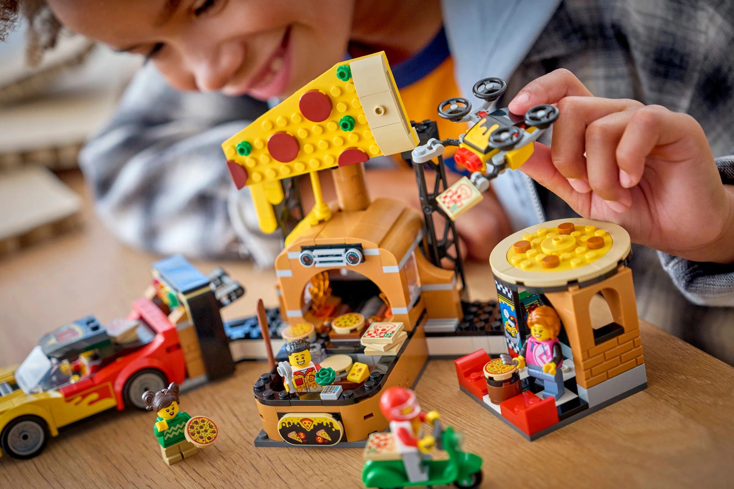 Un copil se joacă cu setul LEGO 60496, experimentând livrarea de pizza.