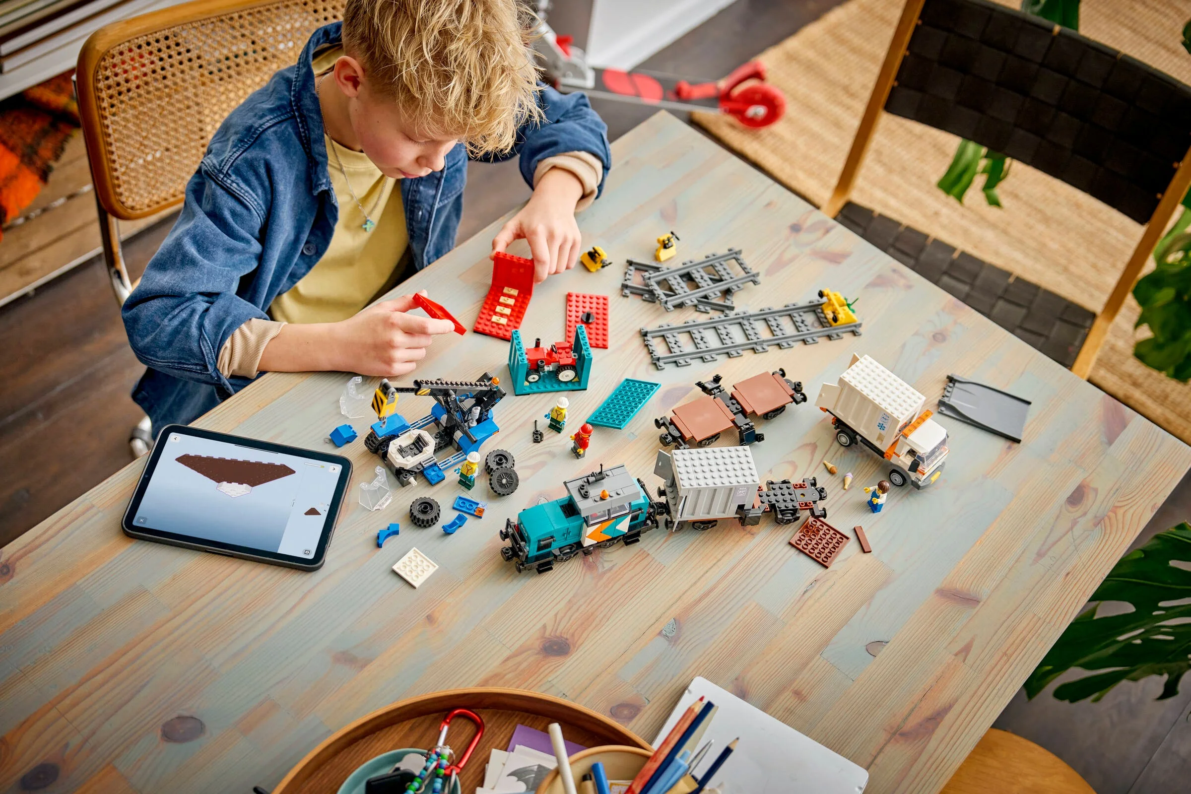 Un băiat construiește trenul de marfă Harbour LEGO 60509. Setul include tren, vagoane și minifigurine.