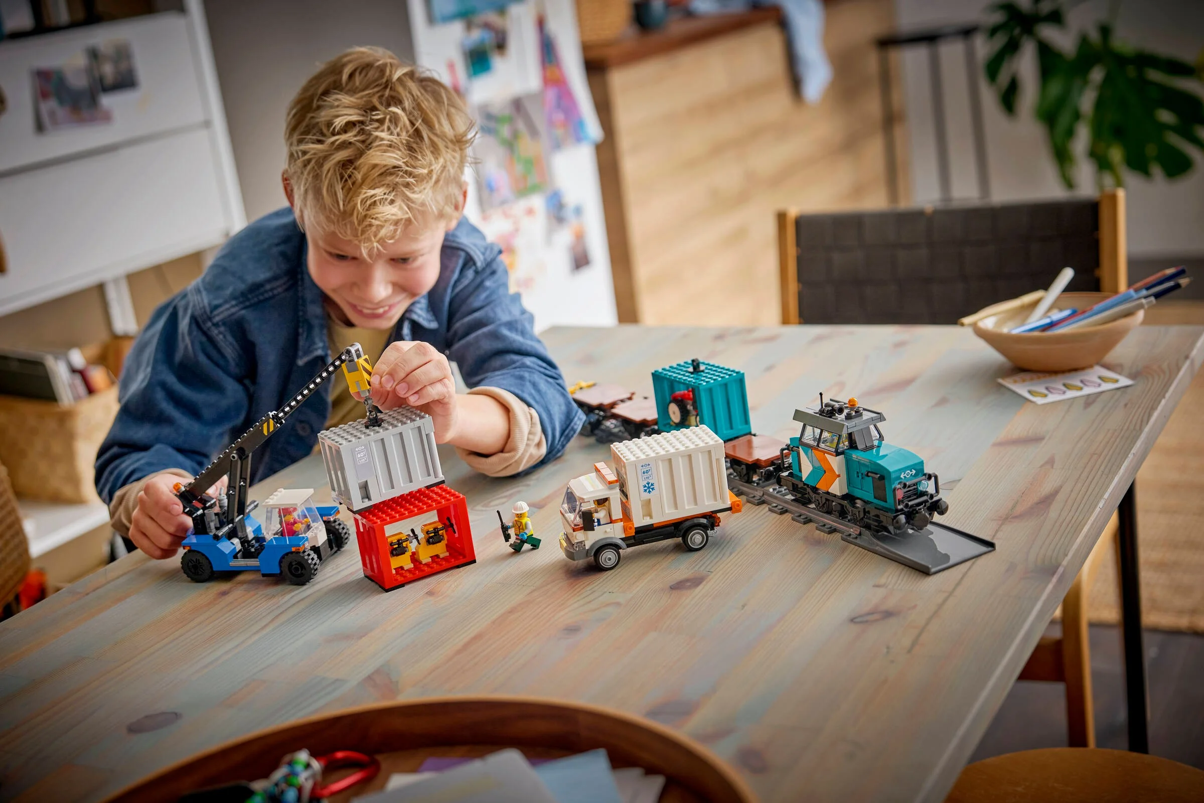 Copil se joacă cu trenul portuar LEGO 60509. Setul include diverse vehicule și minifigurine.