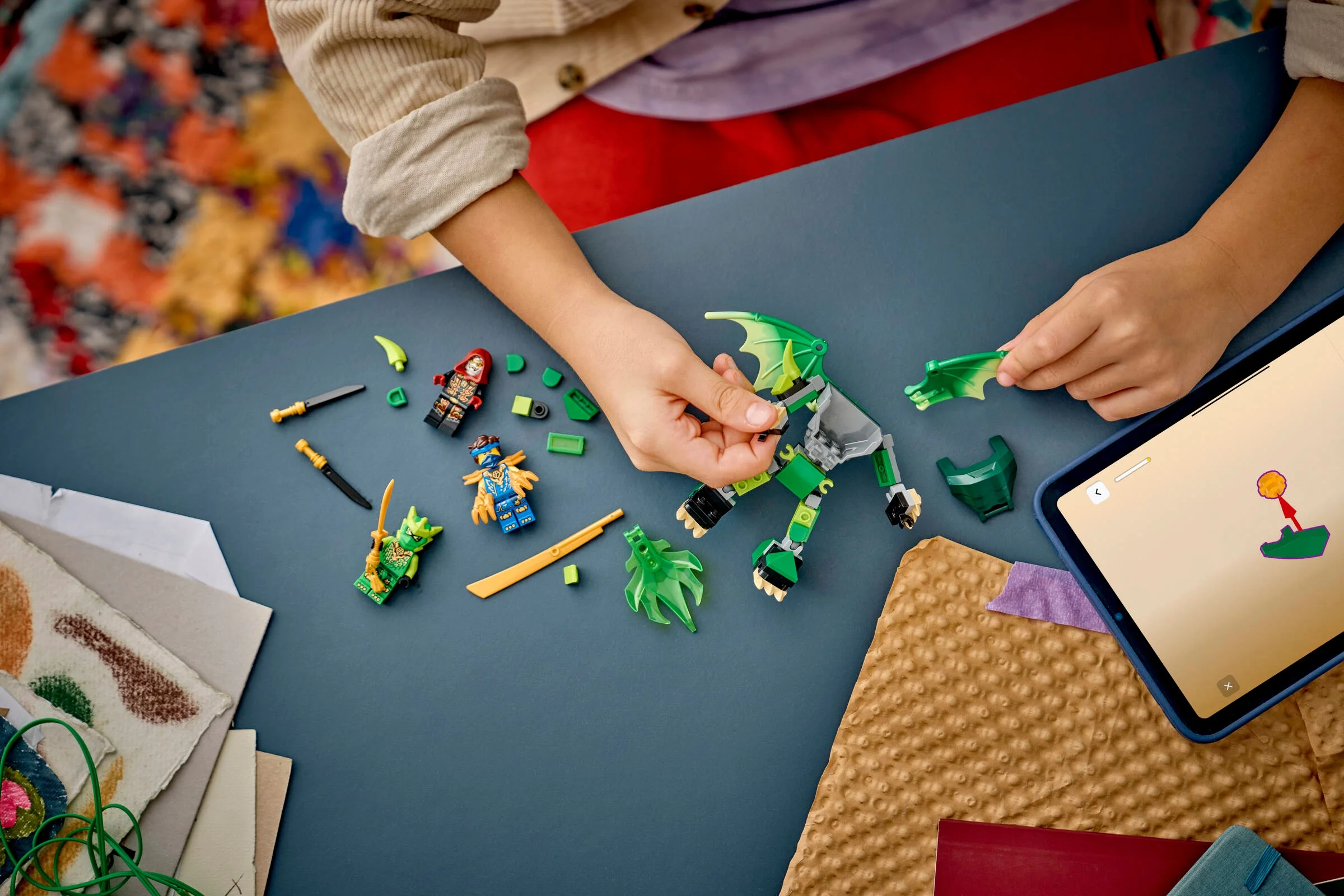 Construcție LEGO Ninjago cu dragonul lui Lloyd și minifigurine. Copilul folosește instrucțiuni digitale.