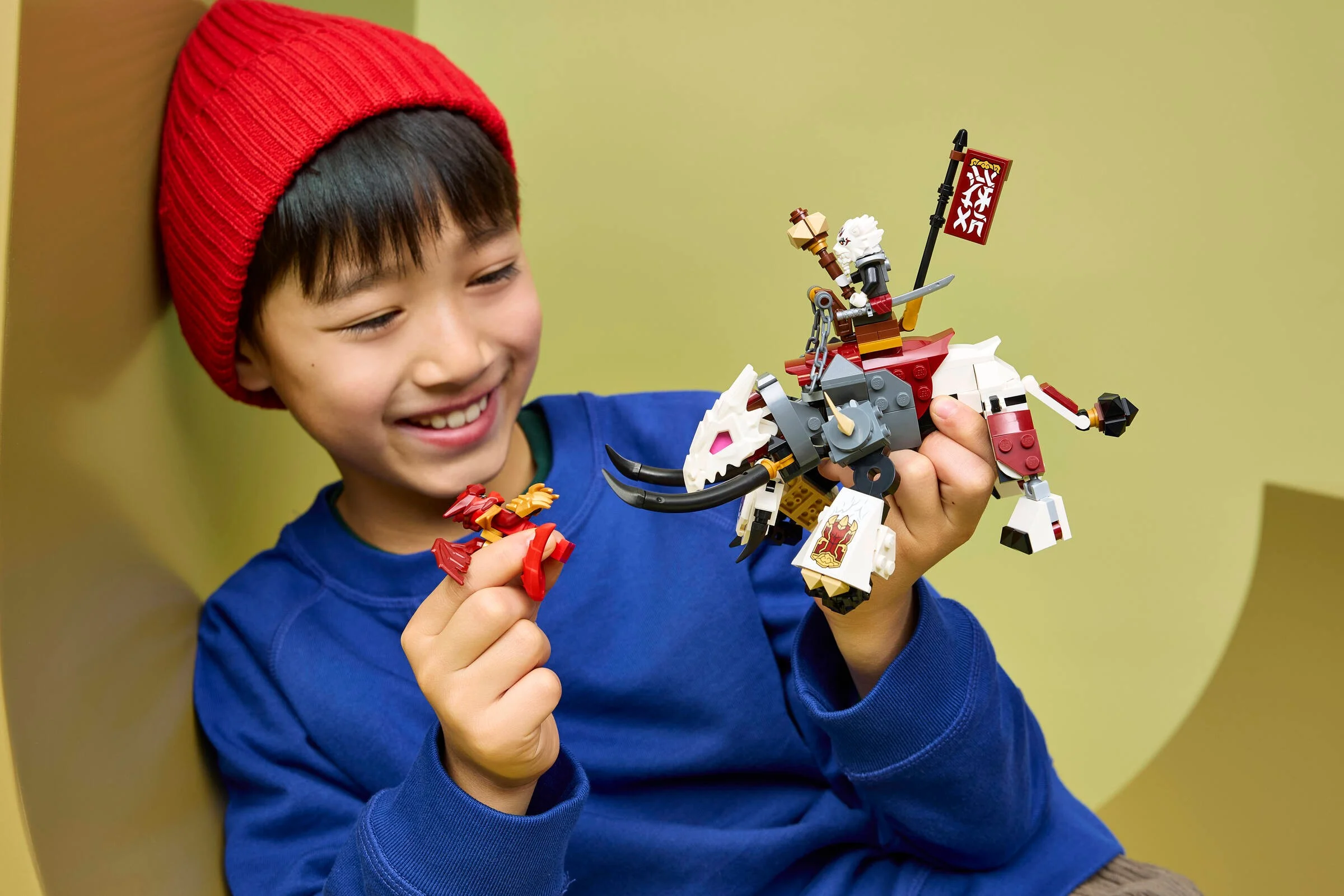 Băiat zâmbitor se joacă cu Zilvar și Grimtak, creând aventuri Ninjago captivante.
