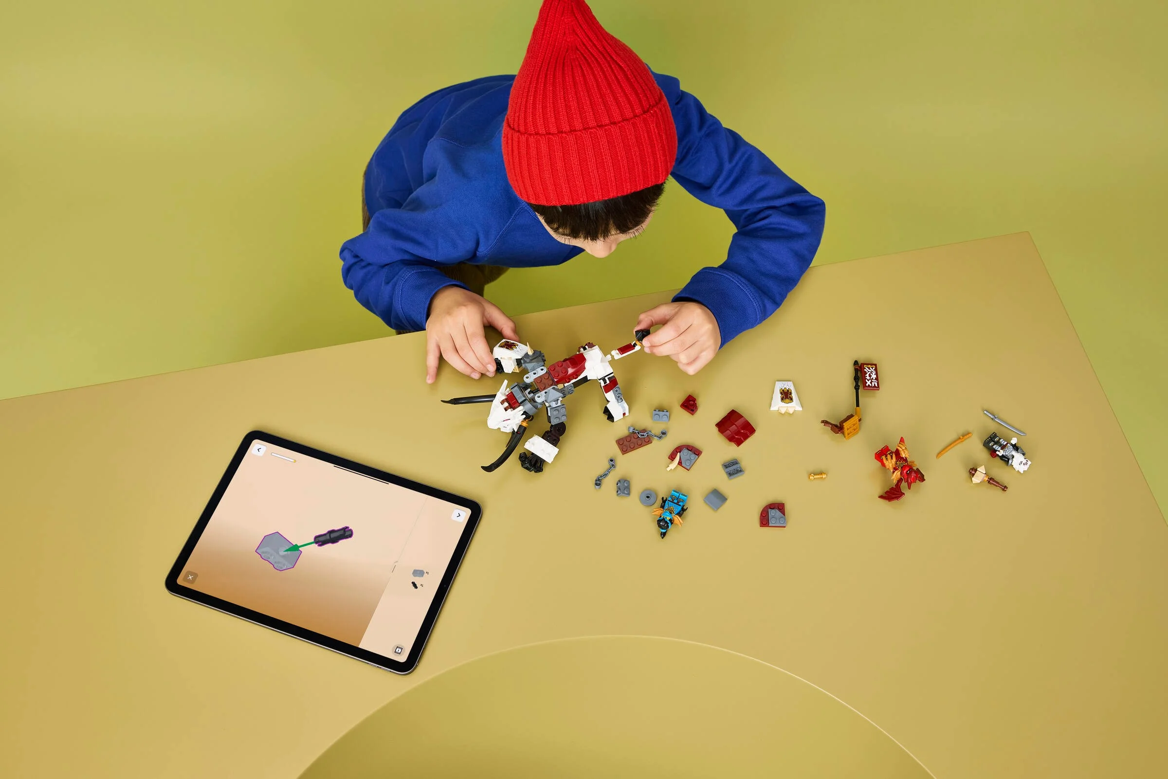 Copil construind setul LEGO Ninjago Zilvar și Grimtak, folosind instrucțiuni digitale.