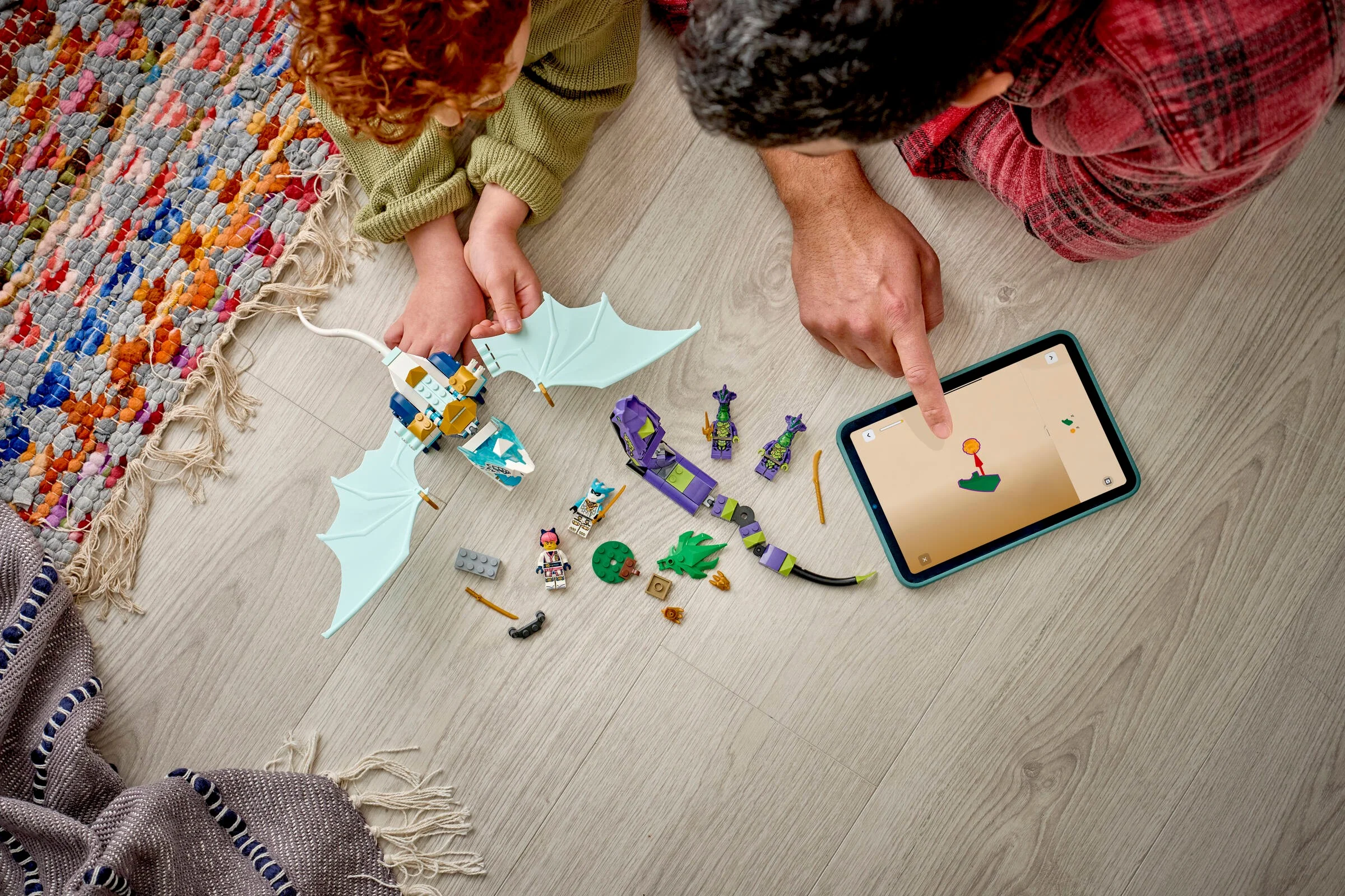 Copii construind setul Zane's Ice Dragon Battle (71865) urmând instrucțiuni pe tabletă.