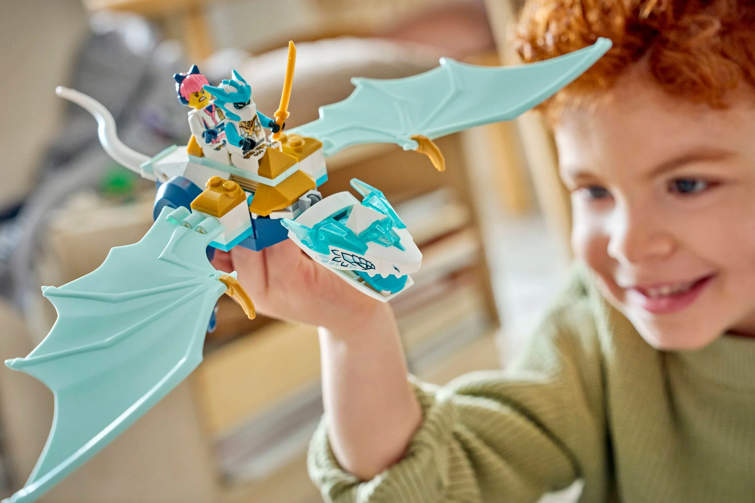 Copil se joacă cu dragonul de gheață LEGO Ninjago, zâmbind.