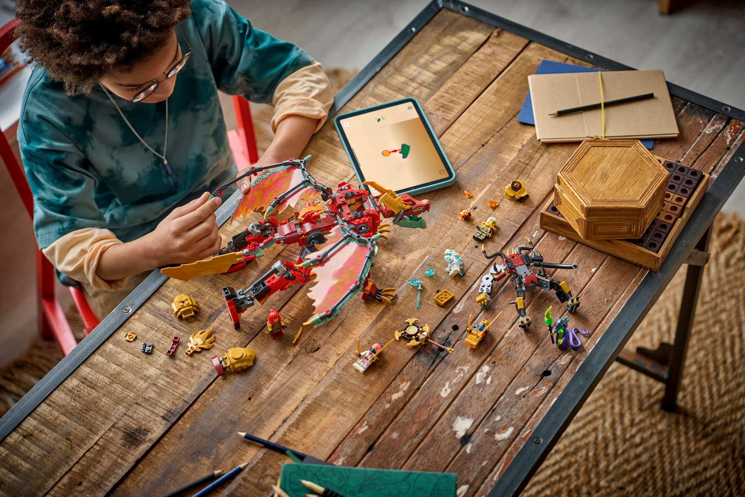 Băiat asamblând setul LEGO Ninjago 71868, cu dragonul transformator Wyldfyre. Instrucțiuni pe tabletă.