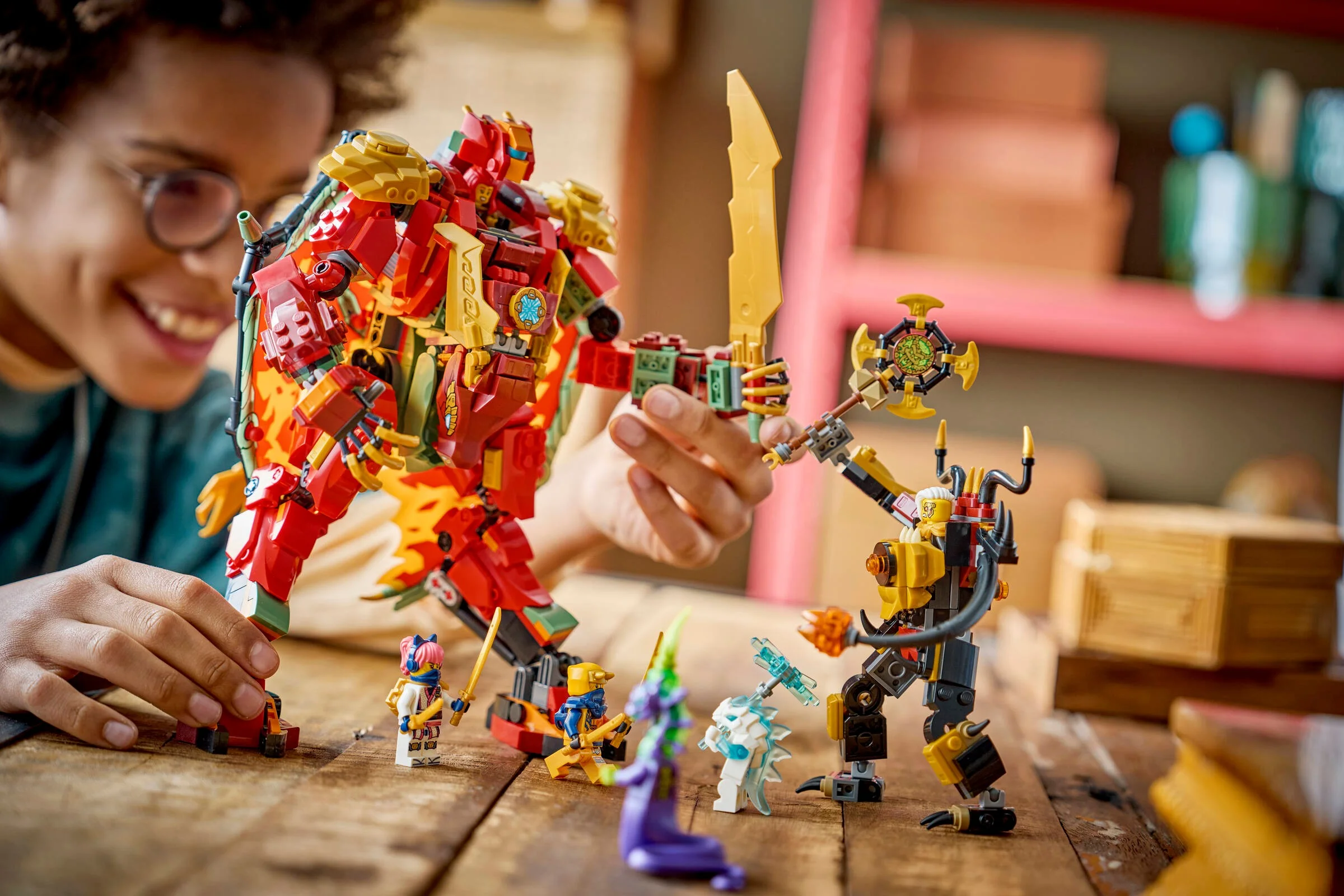 Copil zâmbind joacă cu Wyldfyre și Răufăcătorul în armuri robotizate LEGO Ninjago.