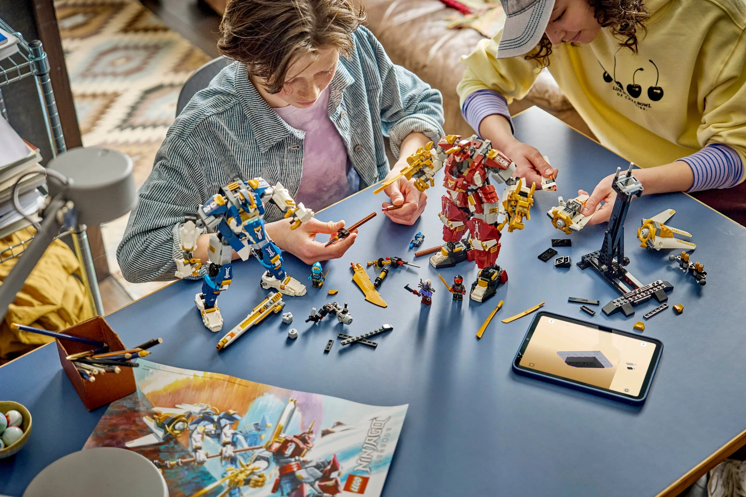 Copii construind setul LEGO Ninjago 71870, doi roboți titan și alte structuri mici, folosind instrucțiuni digitale.