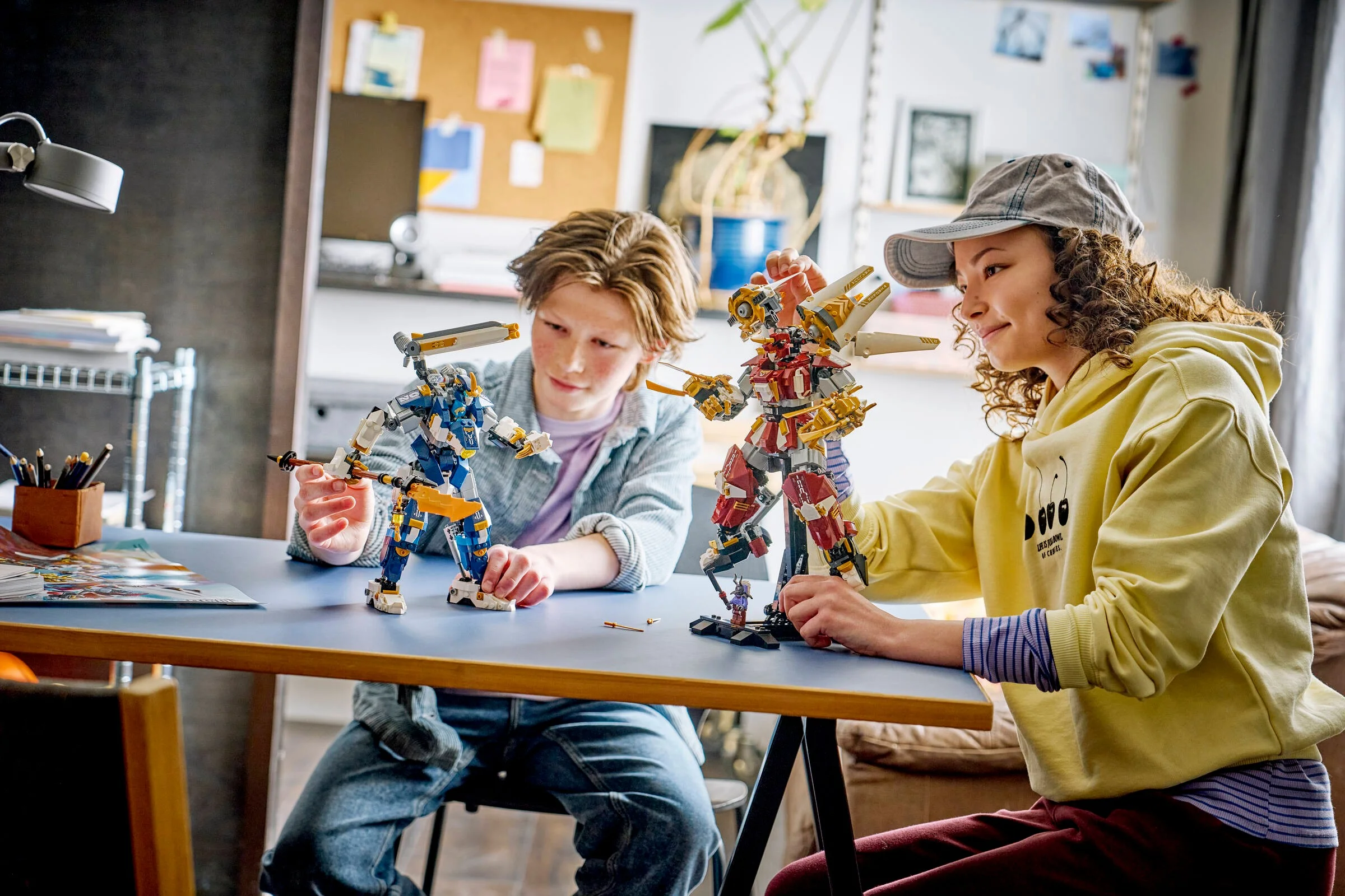 Copii se joacă cu setul LEGO Ninjago 71870, doi roboți titani, pe o masă.