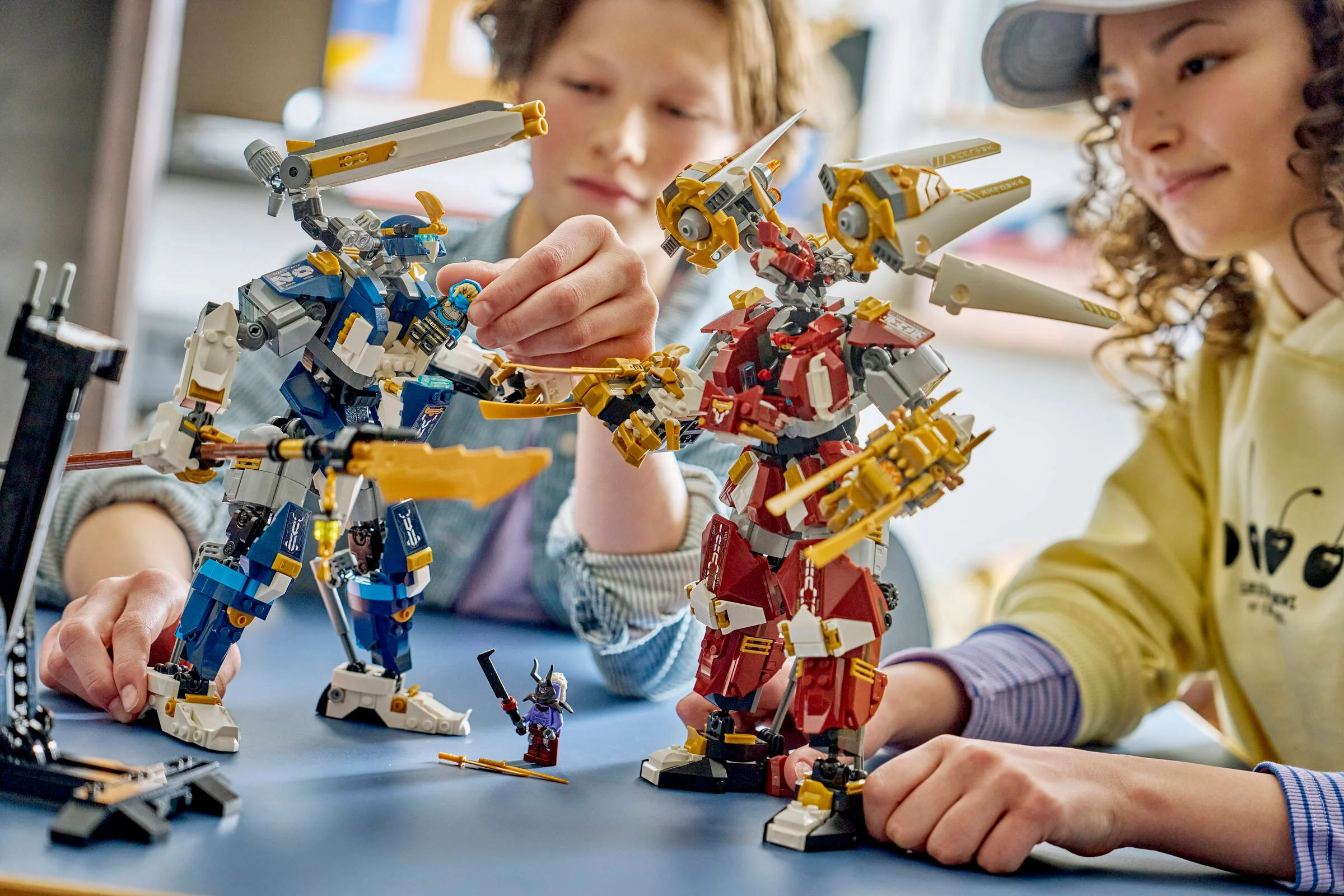 Doi copii se joacă cu roboții LEGO Ninjago, roșu și albastru. Interacțiune și joacă.