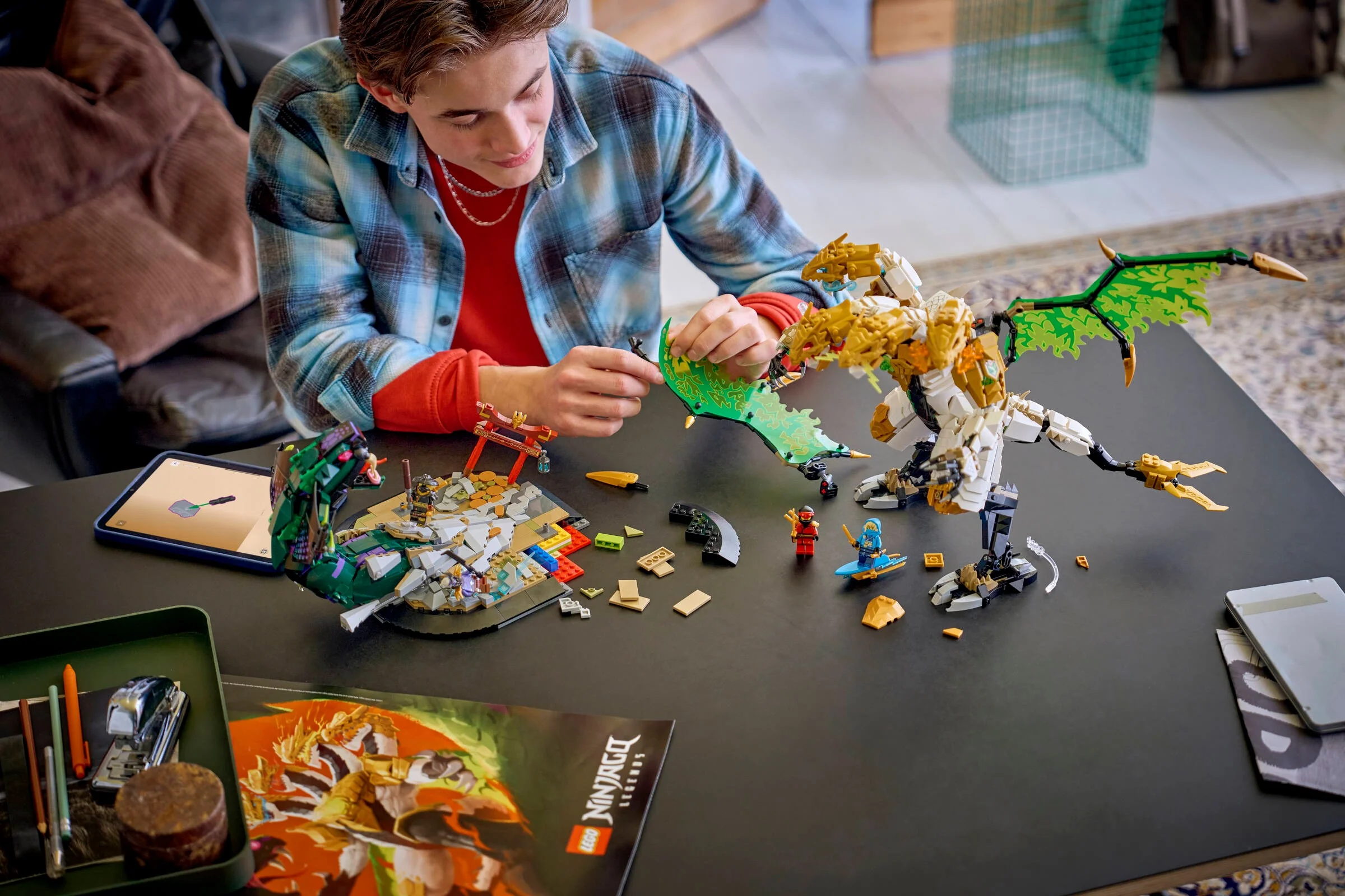 Imagine cu un tânăr construind setul LEGO Ninjago Bătălia Dragonului Ultra, pe o masă.
