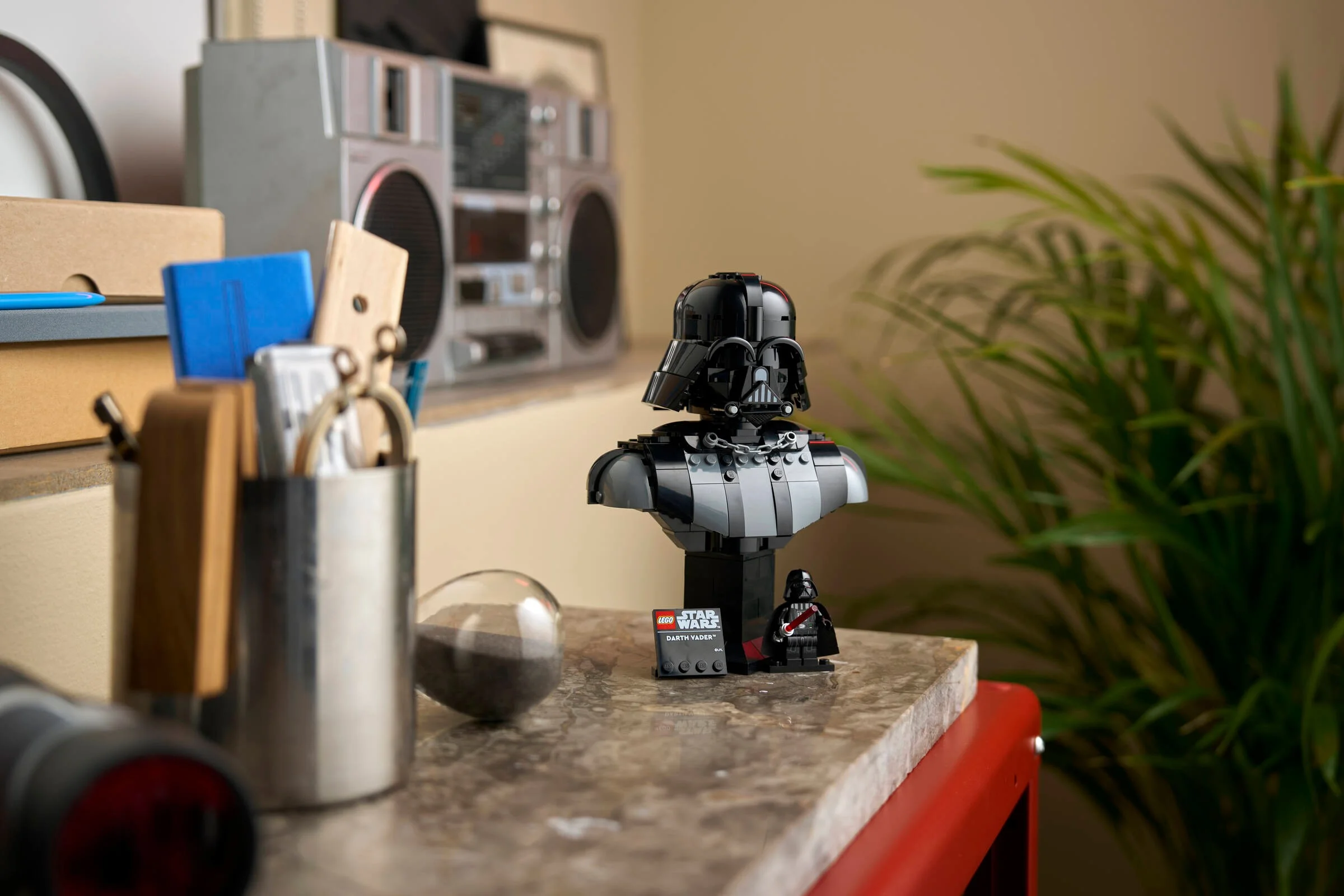 O imagine cu bustul LEGO Darth Vader, pe o suprafață texturată, lângă o mini-figură Darth Vader.