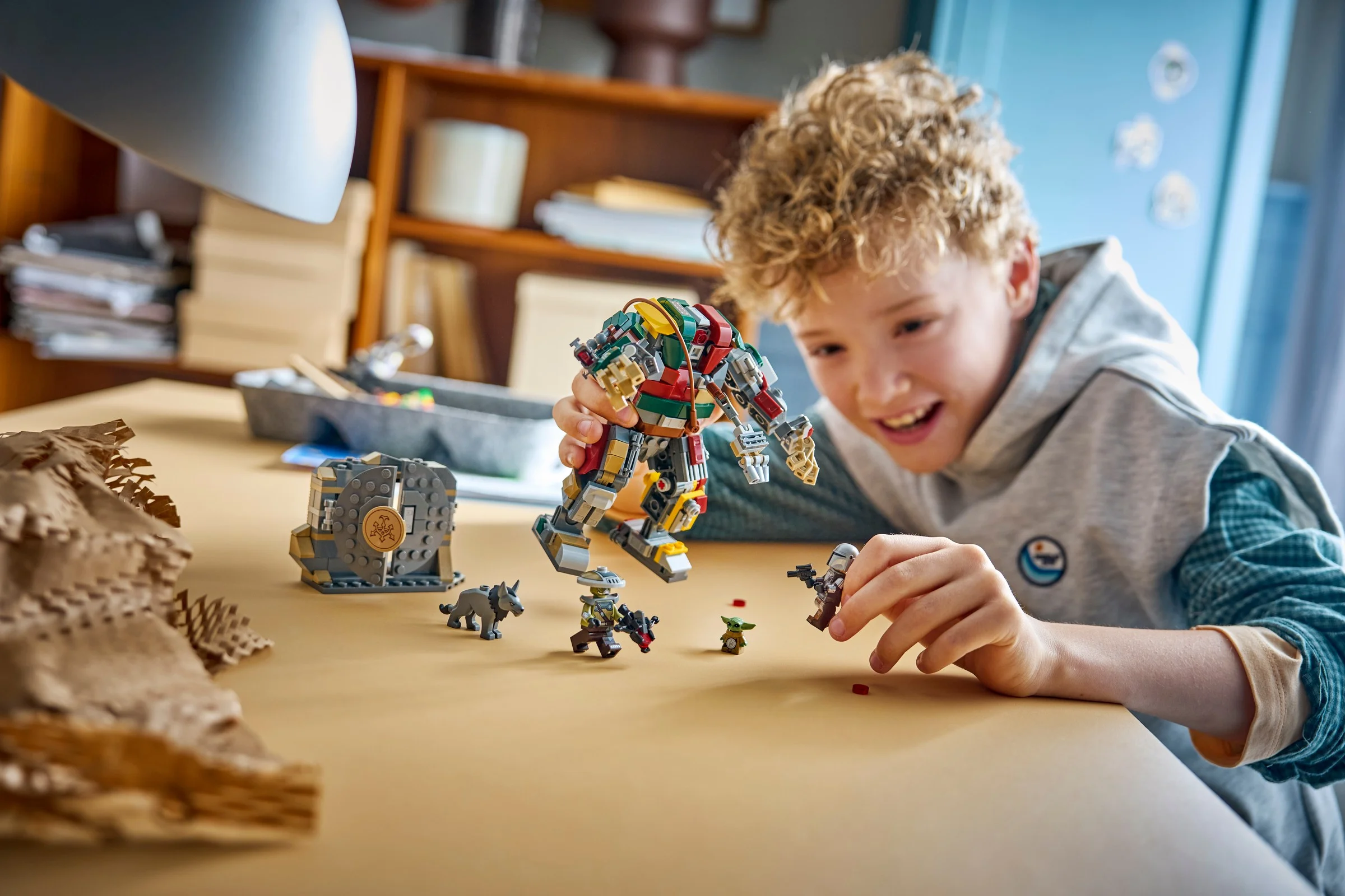 Un copil se joacă cu setul LEGO Hutt Palace Sentry Droid Showdown. Are zâmbetul pe buze.