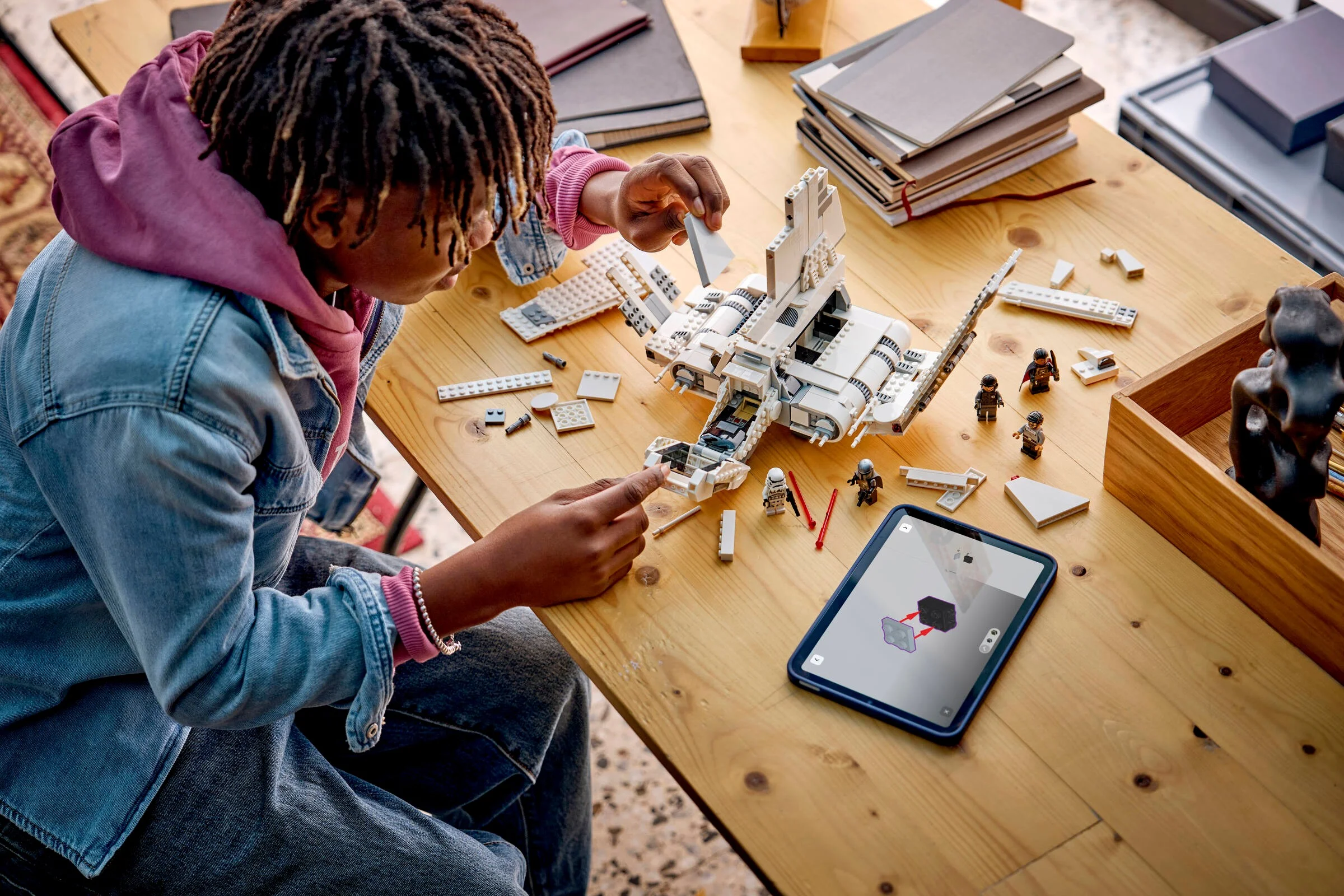 Copil construind naveta Lambda-class din setul LEGO 75459, urmând instrucțiuni digitale.