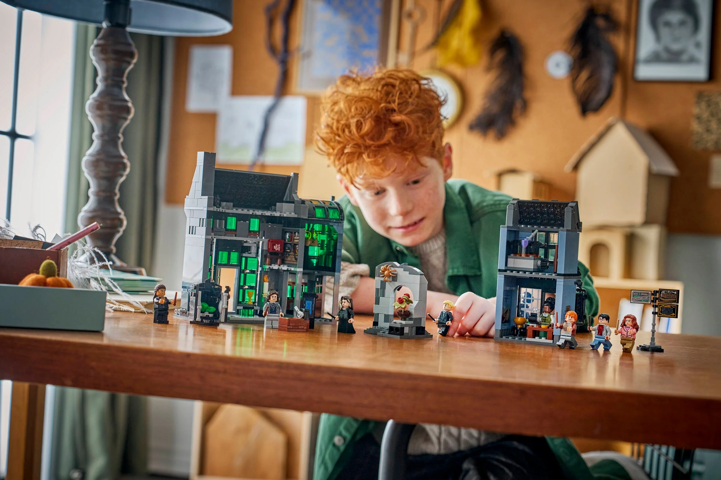 Un băiat se joacă cu setul LEGO 76471, prezentând magazinele din Aleea Încurcată.