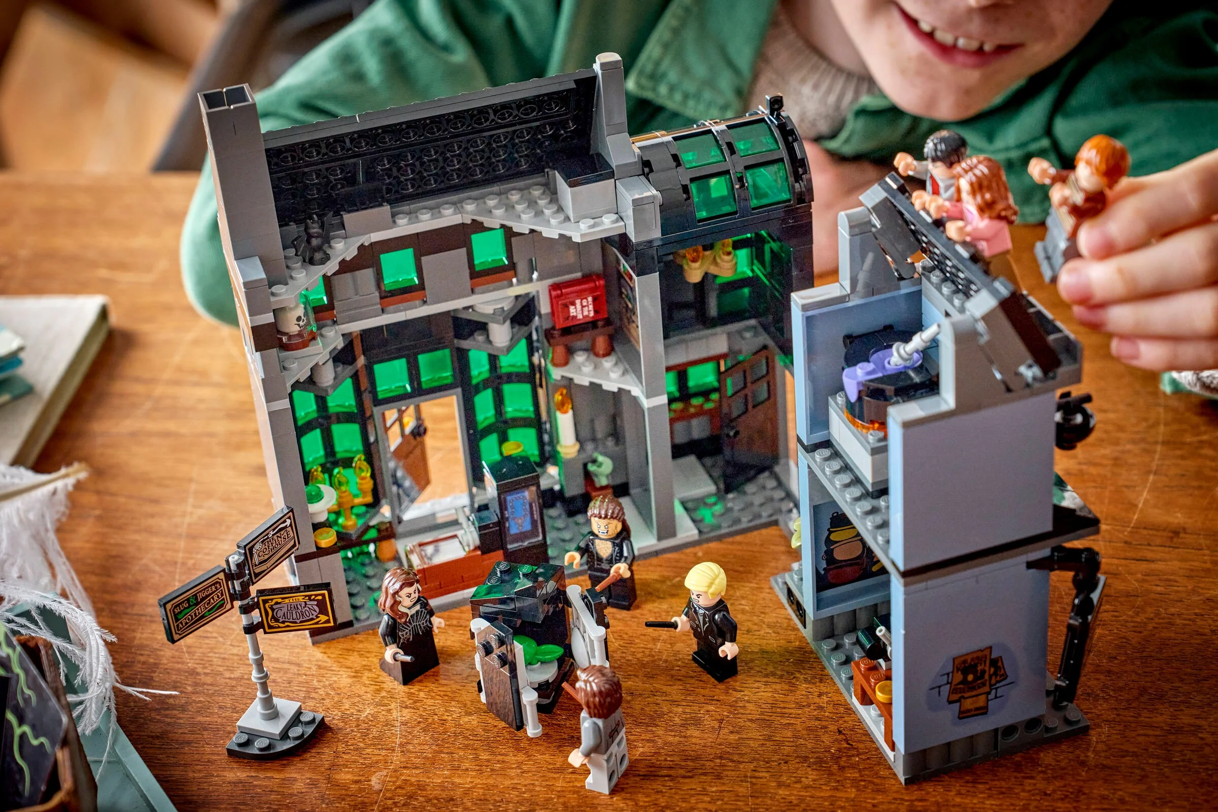 Copil se joacă cu setul LEGO 76471 Aleea Încurcată, cu minifigurine și clădiri detaliate.