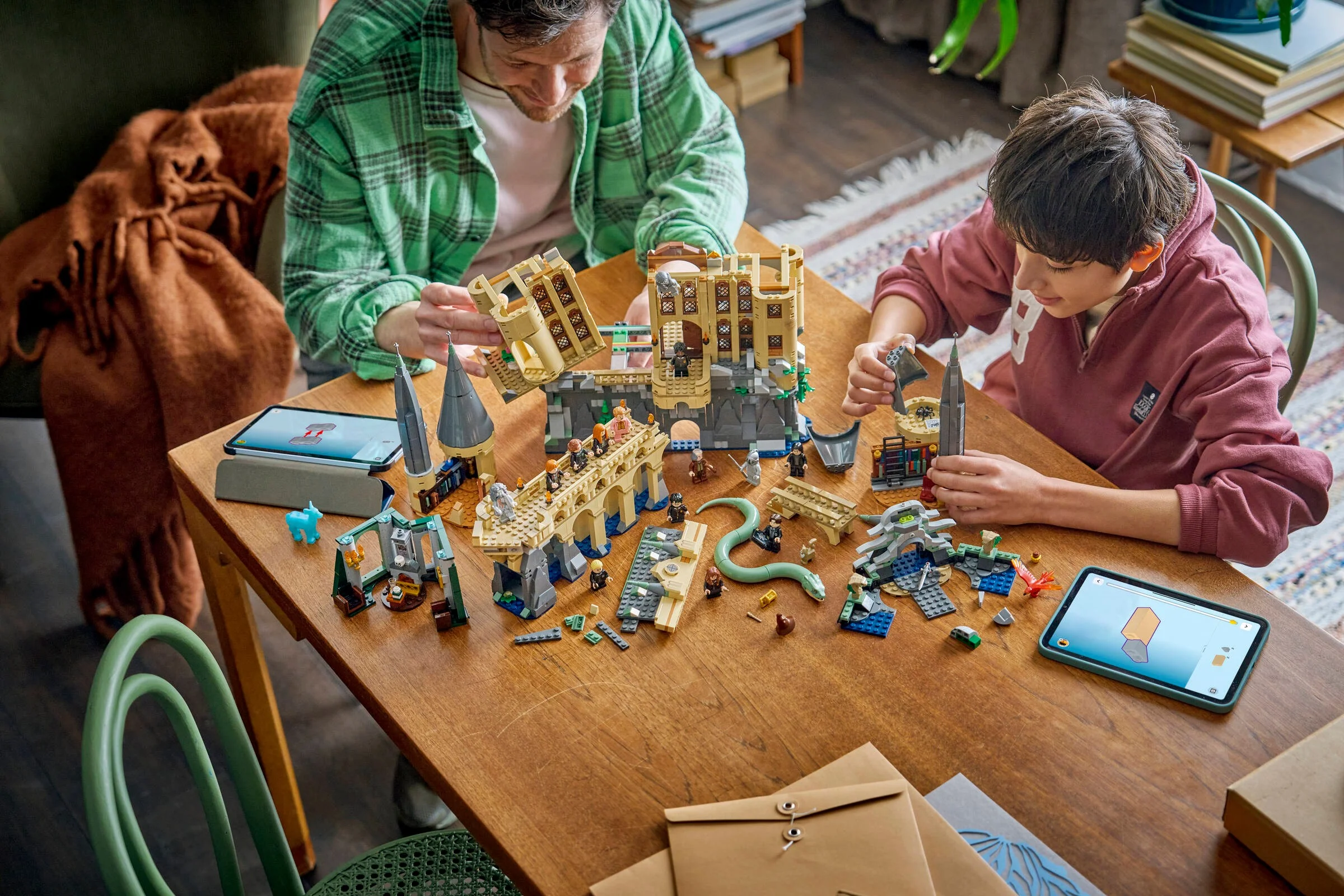 O familie asamblează setul LEGO Hogwarts Castle: East Wing (76473) urmând instrucțiunile de pe tabletă.