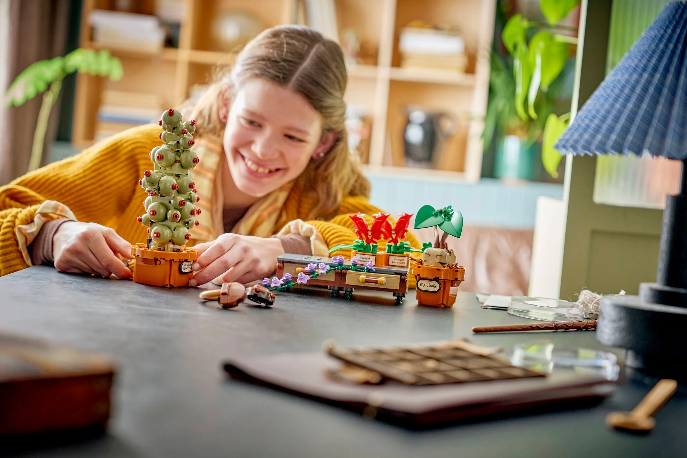 O tânără zâmbește în timp ce se joacă cu setul LEGO cu plante de la Hogwarts.