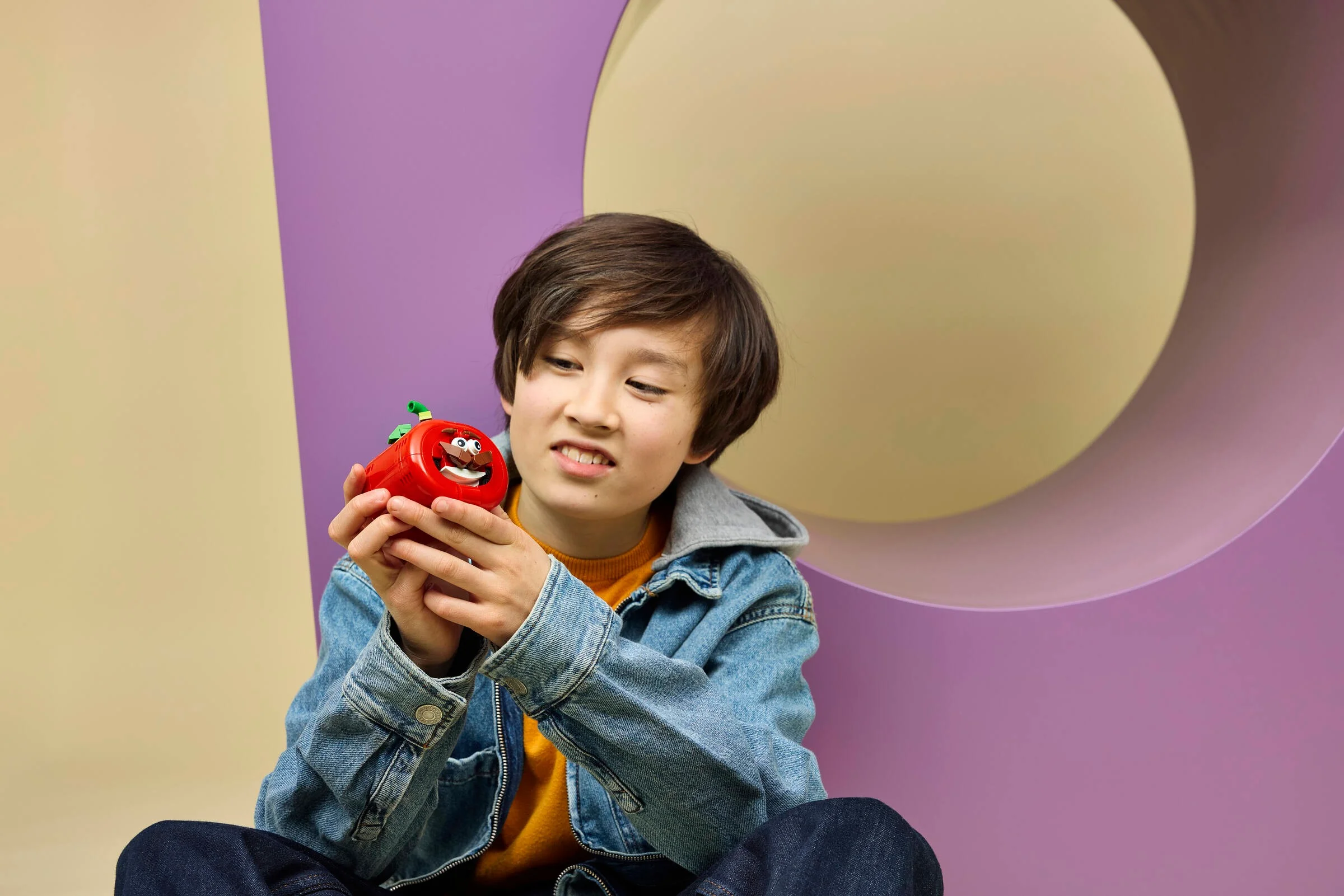 Un copil admiră modelul LEGO Tomatohead, un personaj din Fortnite. Design colorat și expresiv.