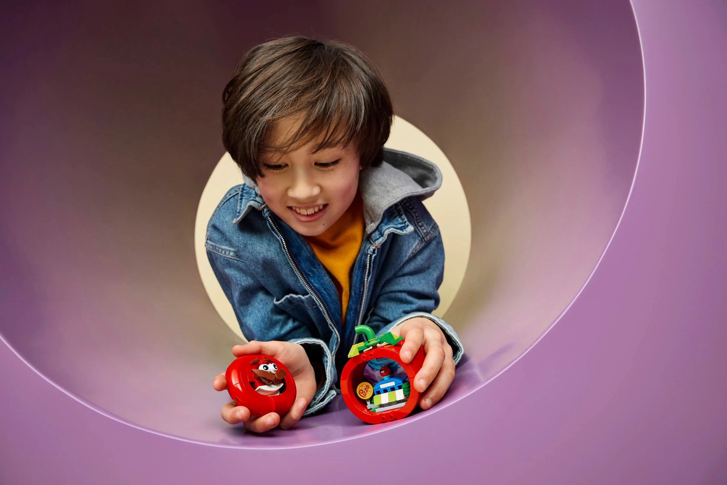 Copil zâmbind, ținând setul LEGO Tomatohead. Design viu, creativitate și distracție la joacă. 