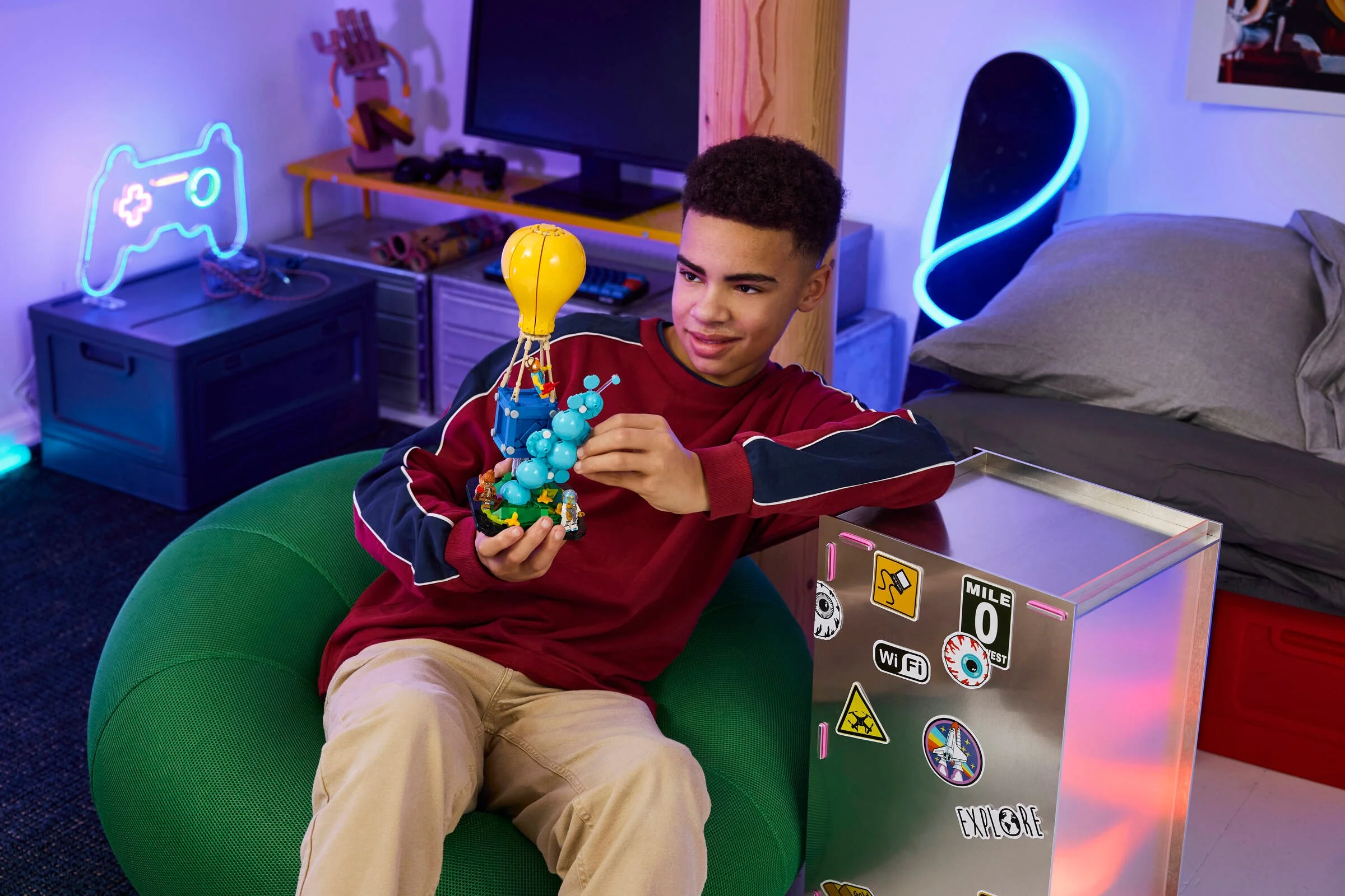 Băiatul se joacă cu setul LEGO Fortnite Supply Drop în camera sa.