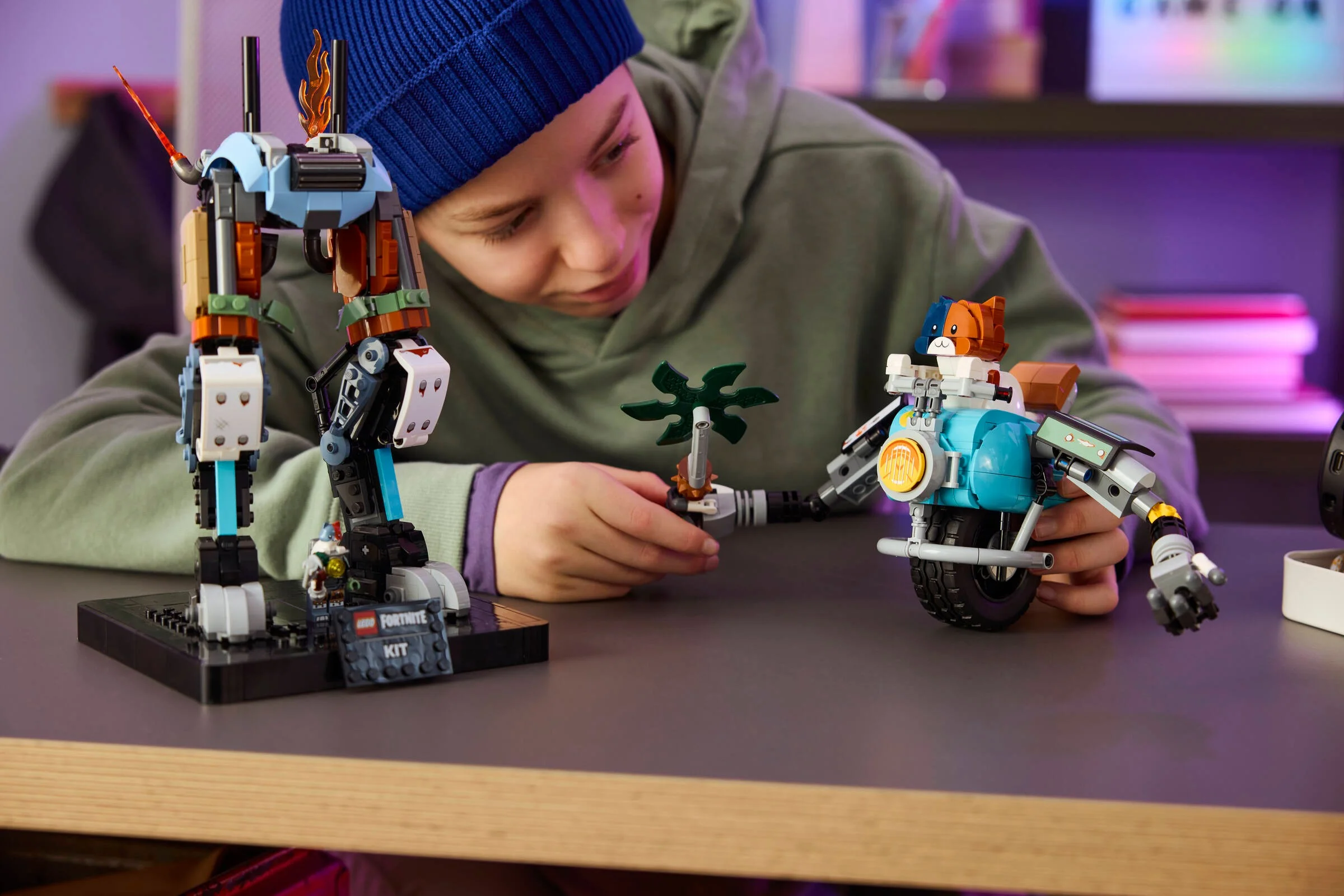 Copilul se joacă cu setul LEGO Fortnite. Robotul și motocicleta Meowscles sunt vizibile.