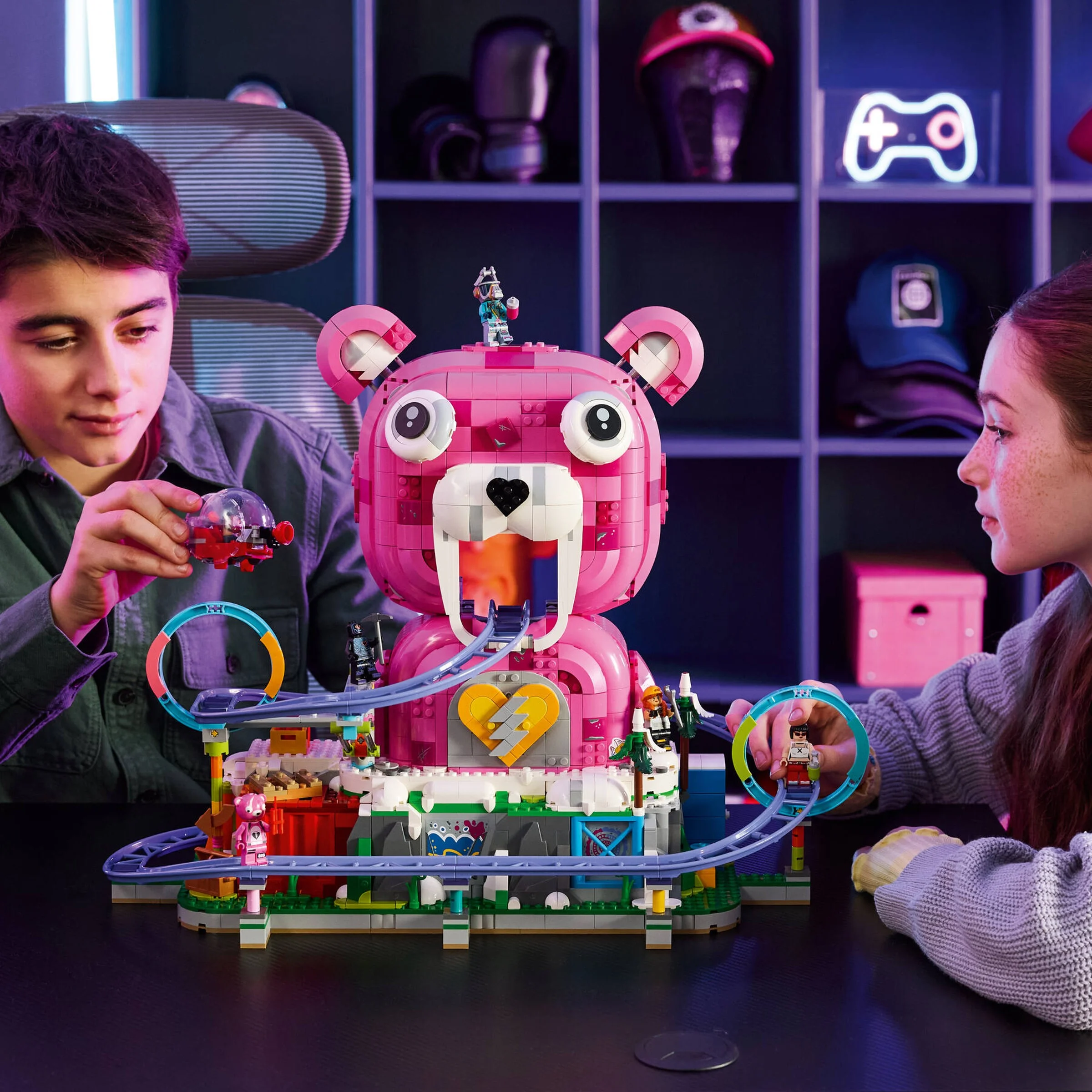 Copii se joacă cu setul LEGO 77082, „Peștera Rave”. Un model mare roz, cu un roller-coaster.