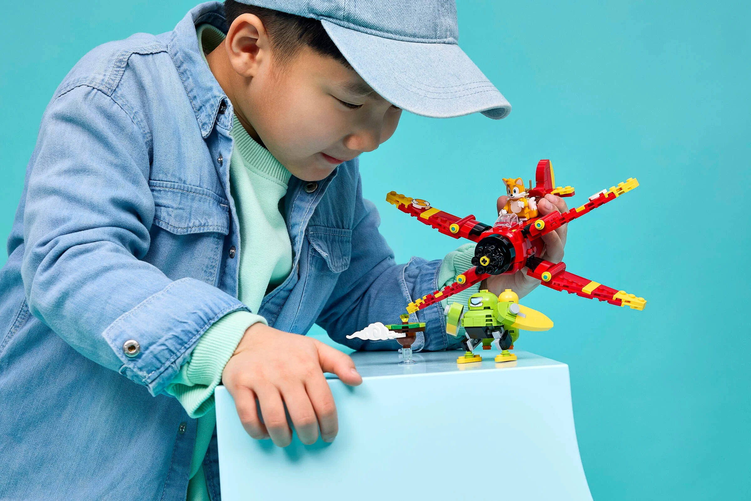 Băiat se uită cu atenție la avionul lui Tails, din setul LEGO Sonic. Încântare!
