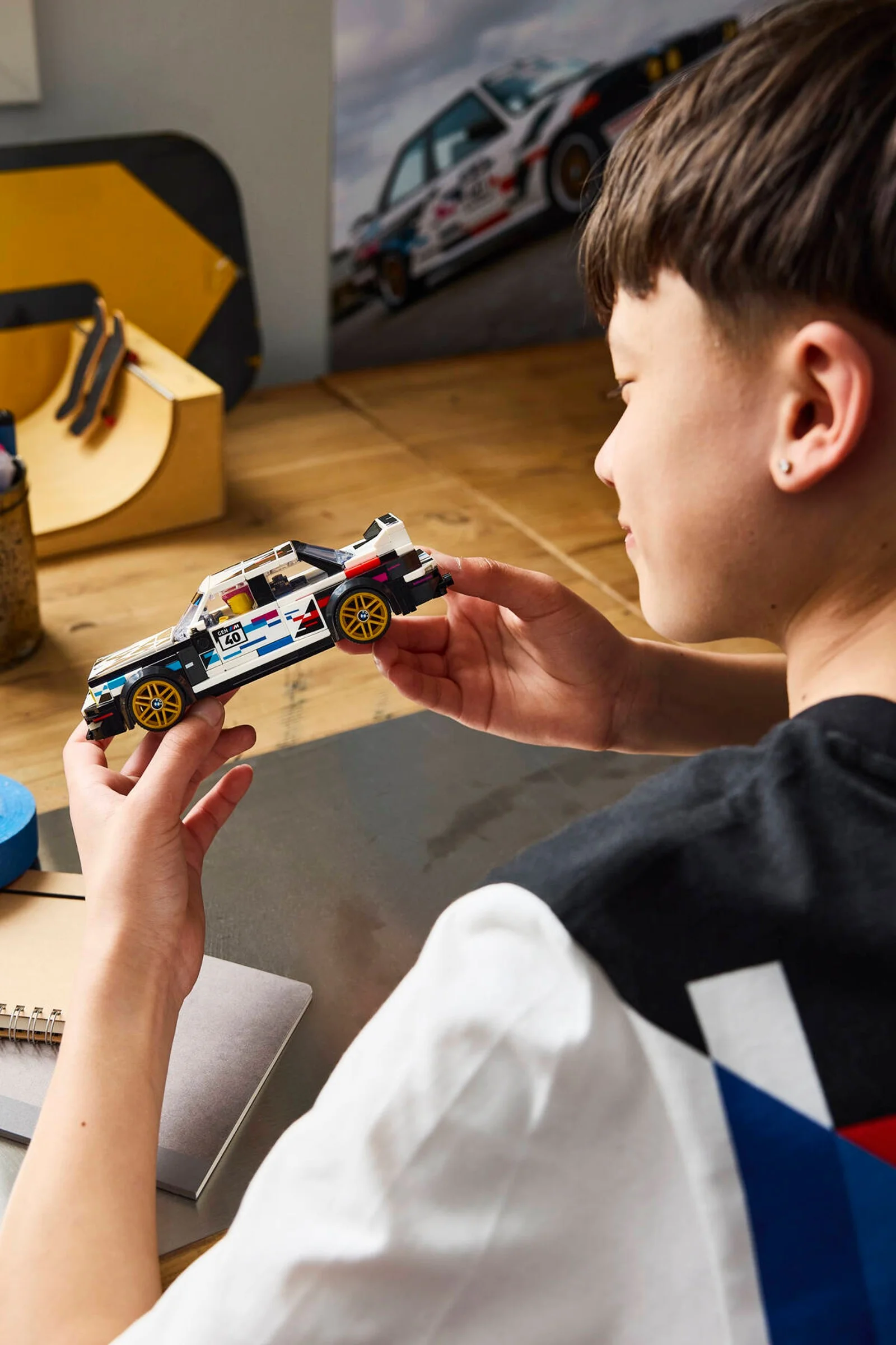 Băiat admirând modelul LEGO BMW M3 (E30), detaliu plăcut și pasiune pentru mașini.
