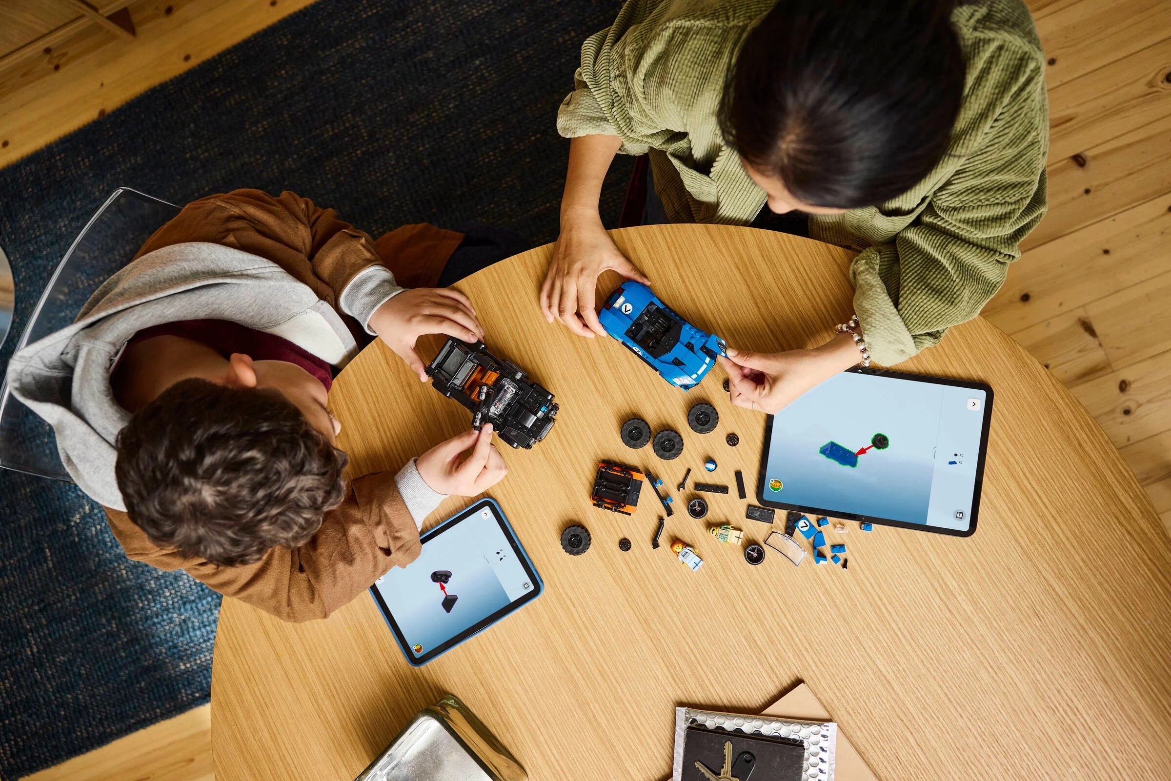 Copii construind mașinile LEGO Jaguar și Land Rover, urmând instrucțiuni digitale pe tabletă.