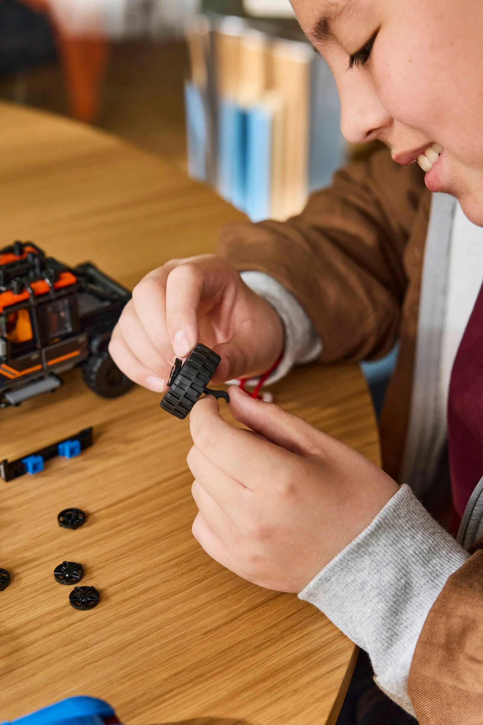 Copil asamblând roțile modelului Land Rover Defender Classic LEGO.