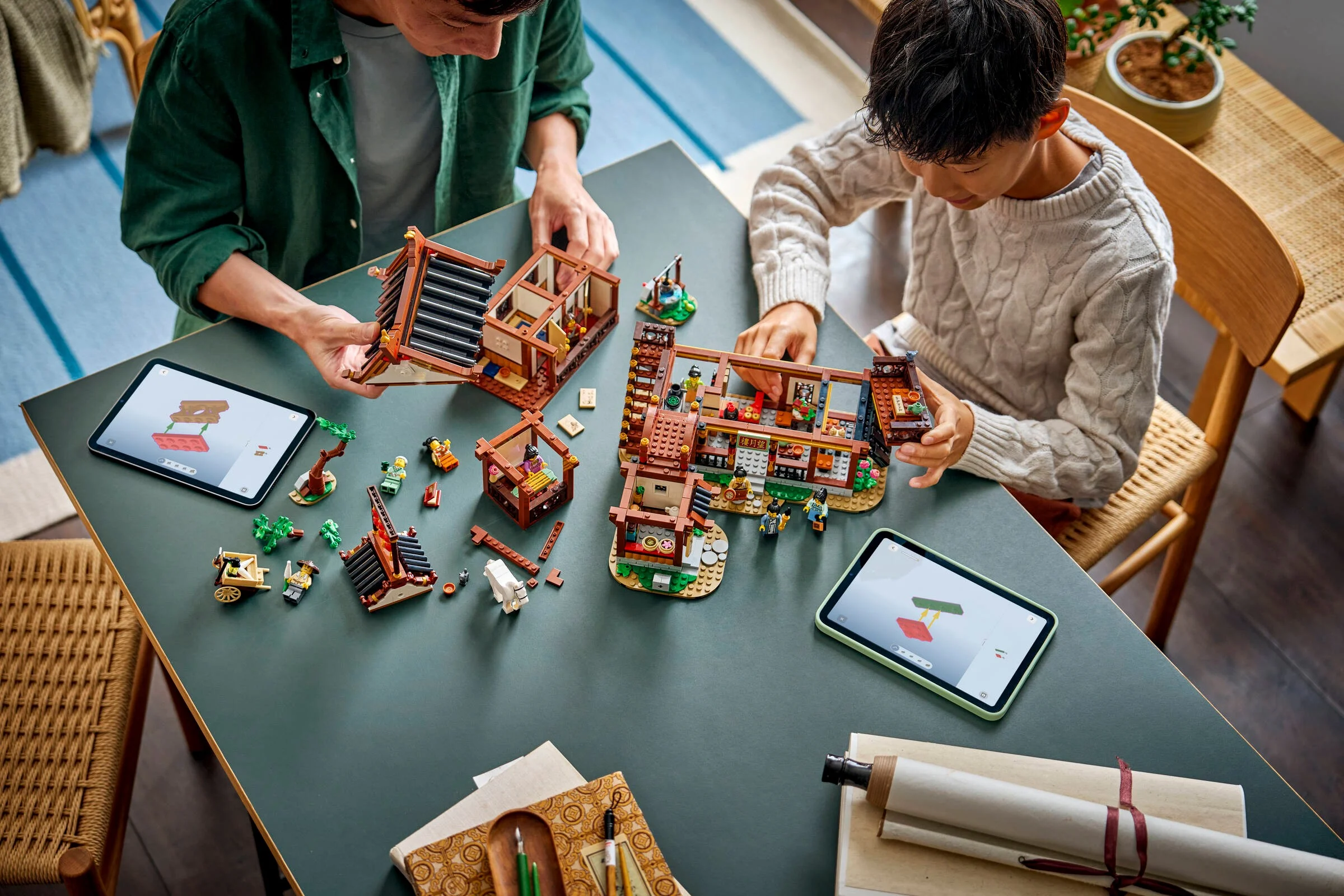 Doi oameni construiesc setul LEGO Hanul Vechi pentru Observarea Lunii, 80121.