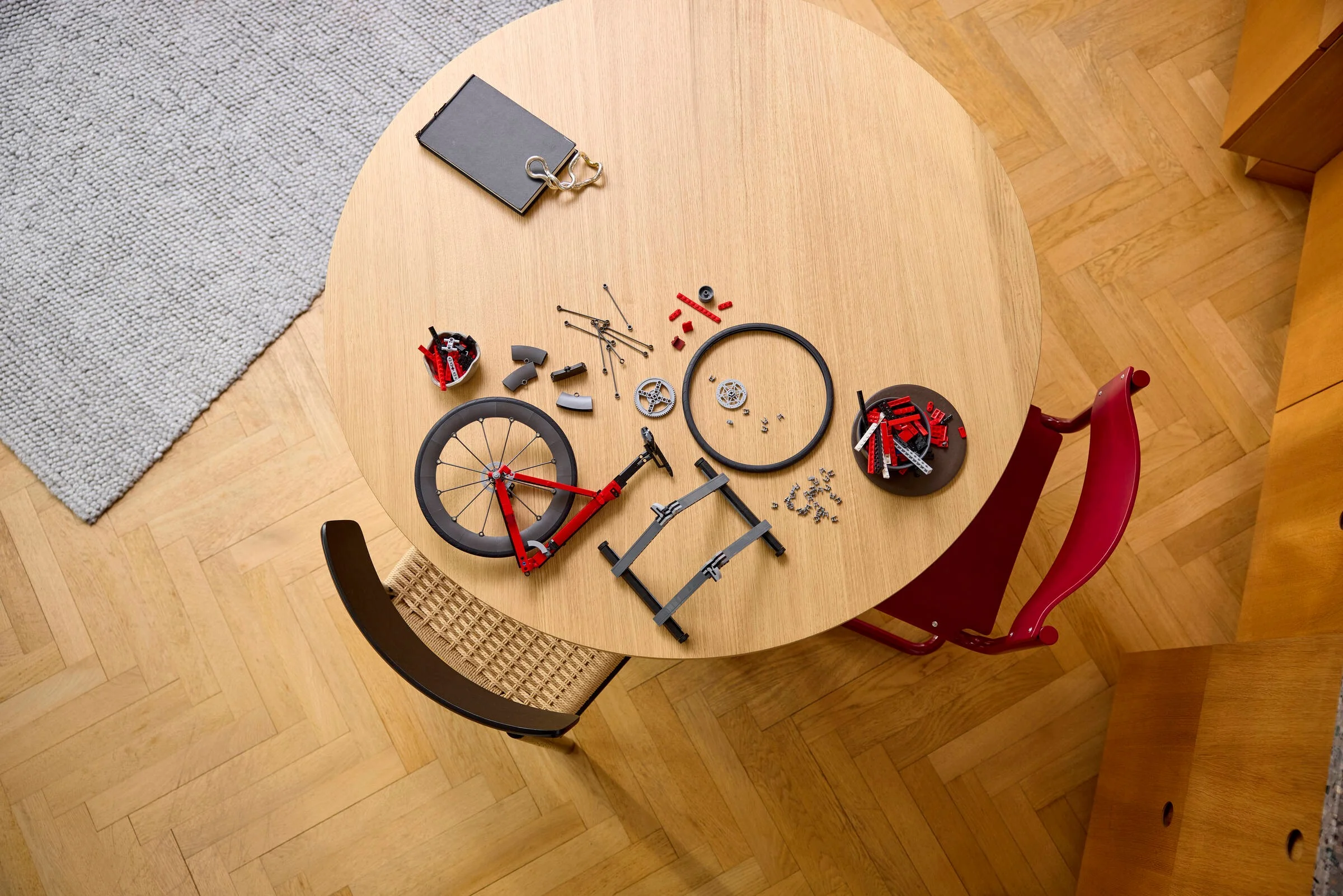 Componente LEGO împrăștiate pe o masă rotundă, pregătite pentru asamblarea unei biciclete.