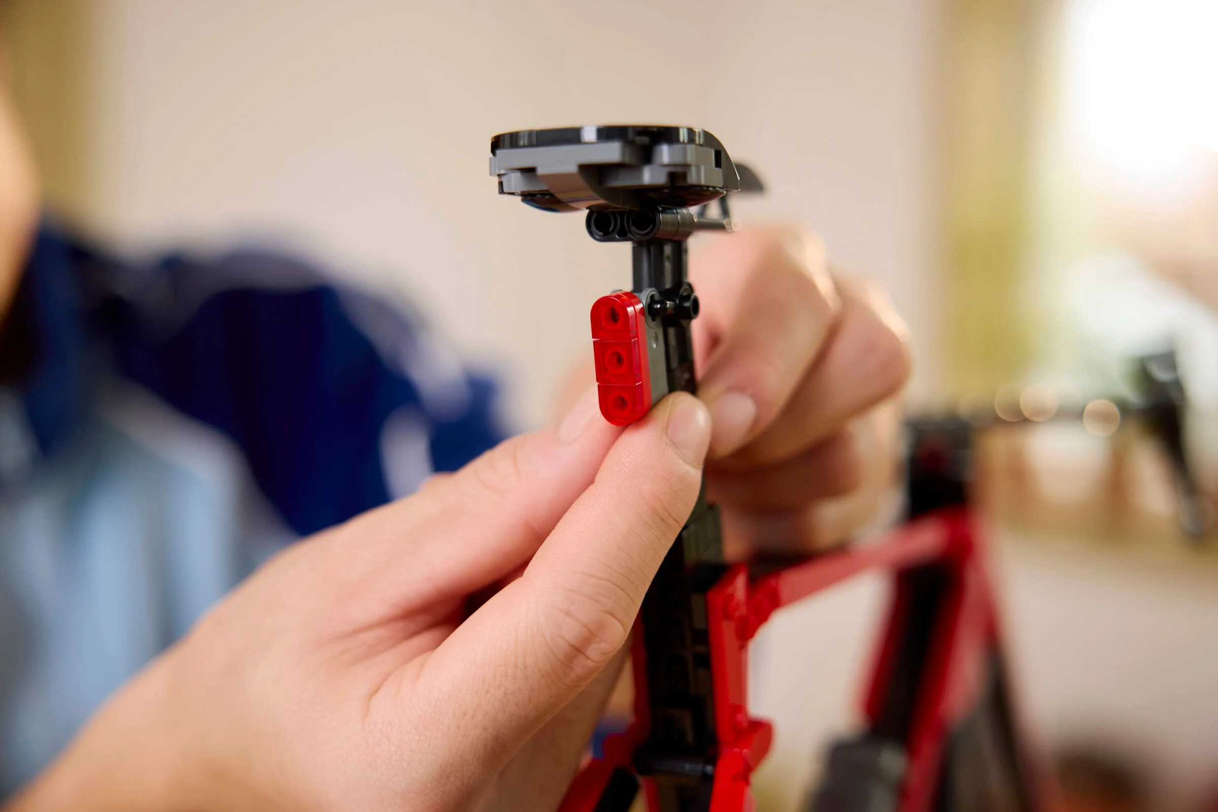 Detalii ale asamblării bicicletei LEGO, se montează stopul roșu. Imagine detaliată.