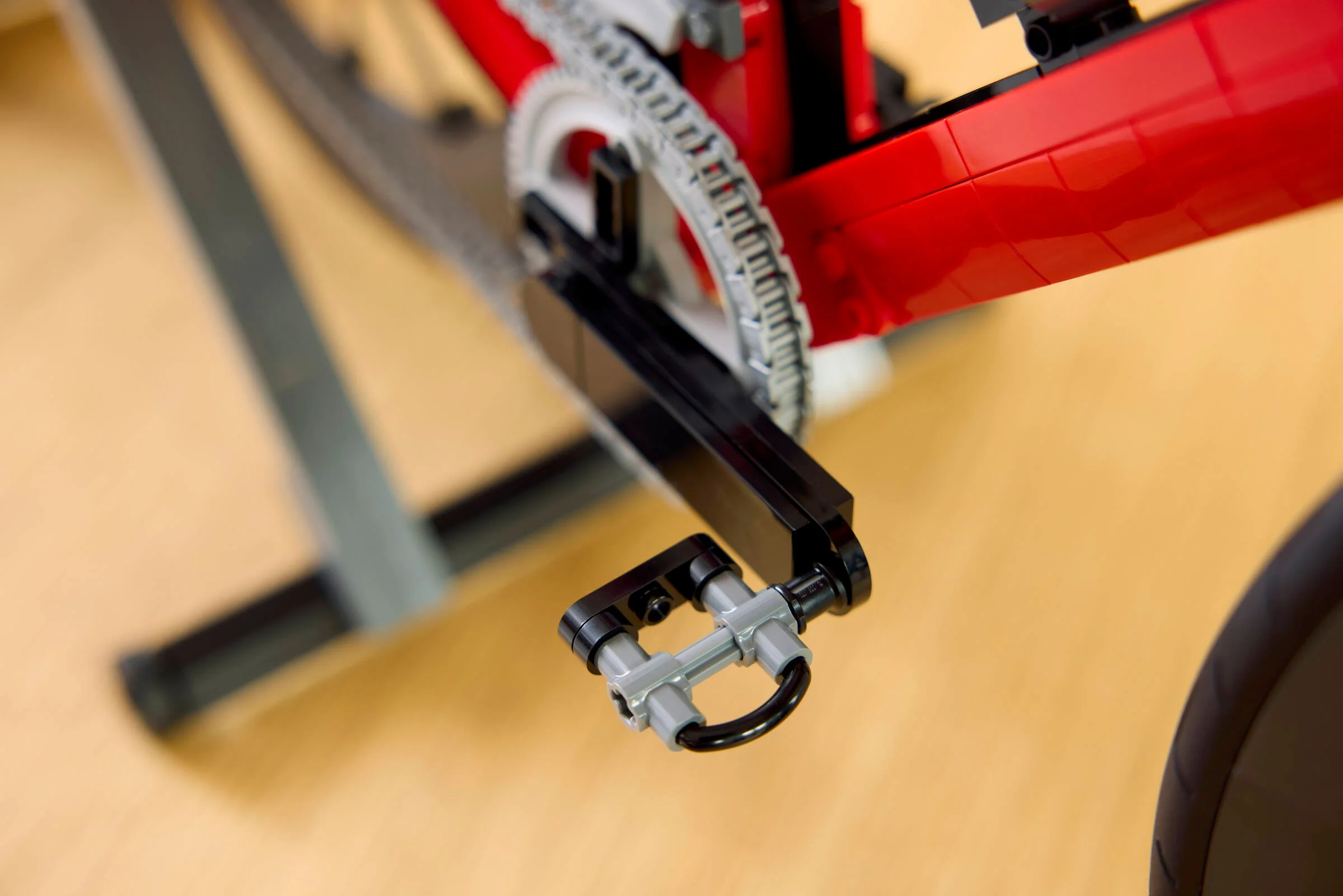 Prim-plan detaliat al pedalei, lanțului și cadrului roșu al bicicletei LEGO.