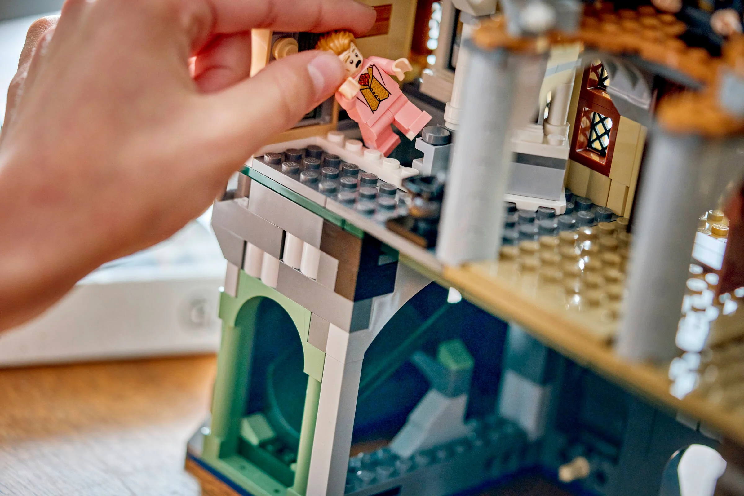 Construirea aripii estice a Castelului Hogwarts LEGO, cu o minifigurină așezată.