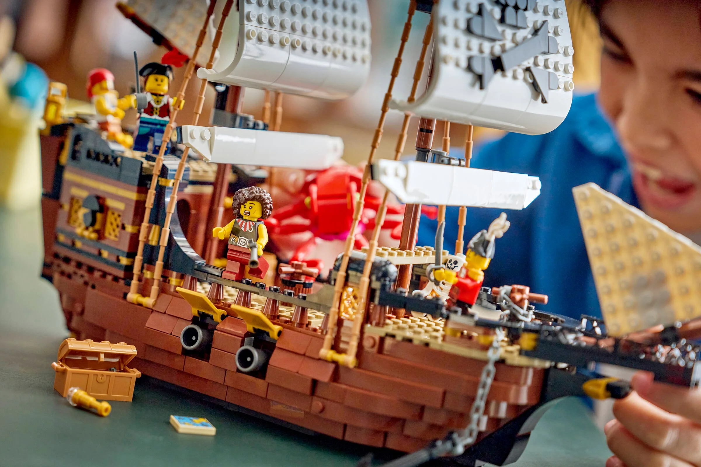 O imagine a setului LEGO corabie pirat, cu o fată în fundal, concentrându-se pe detalii.