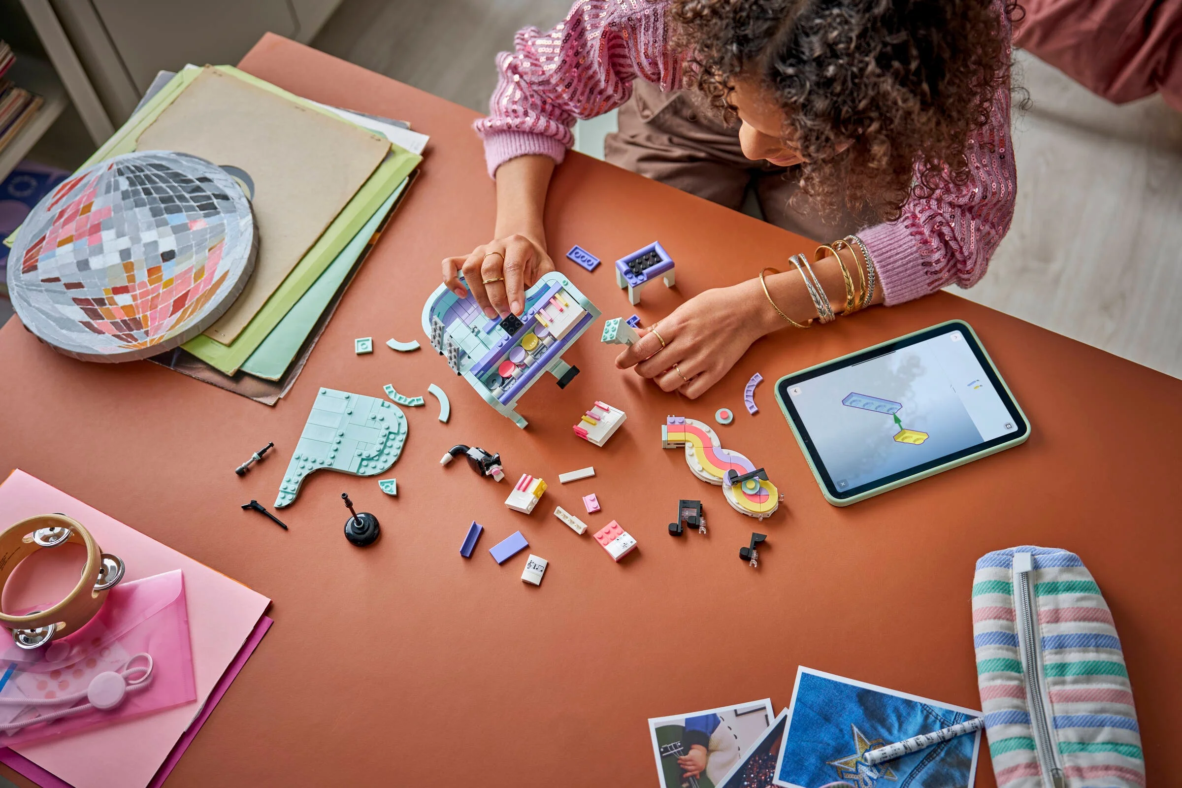 Imagine cu o persoană asamblând pianul LEGO® 31392. Detalii despre piese și instrucțiuni pe tabletă.