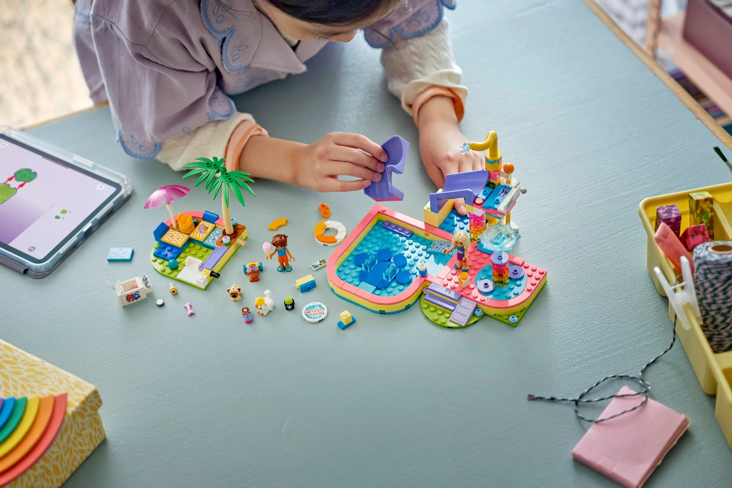 Fată construind parcul acvatic LEGO Friends. Set colorat, distractiv, cu tobogane și detalii minunate.