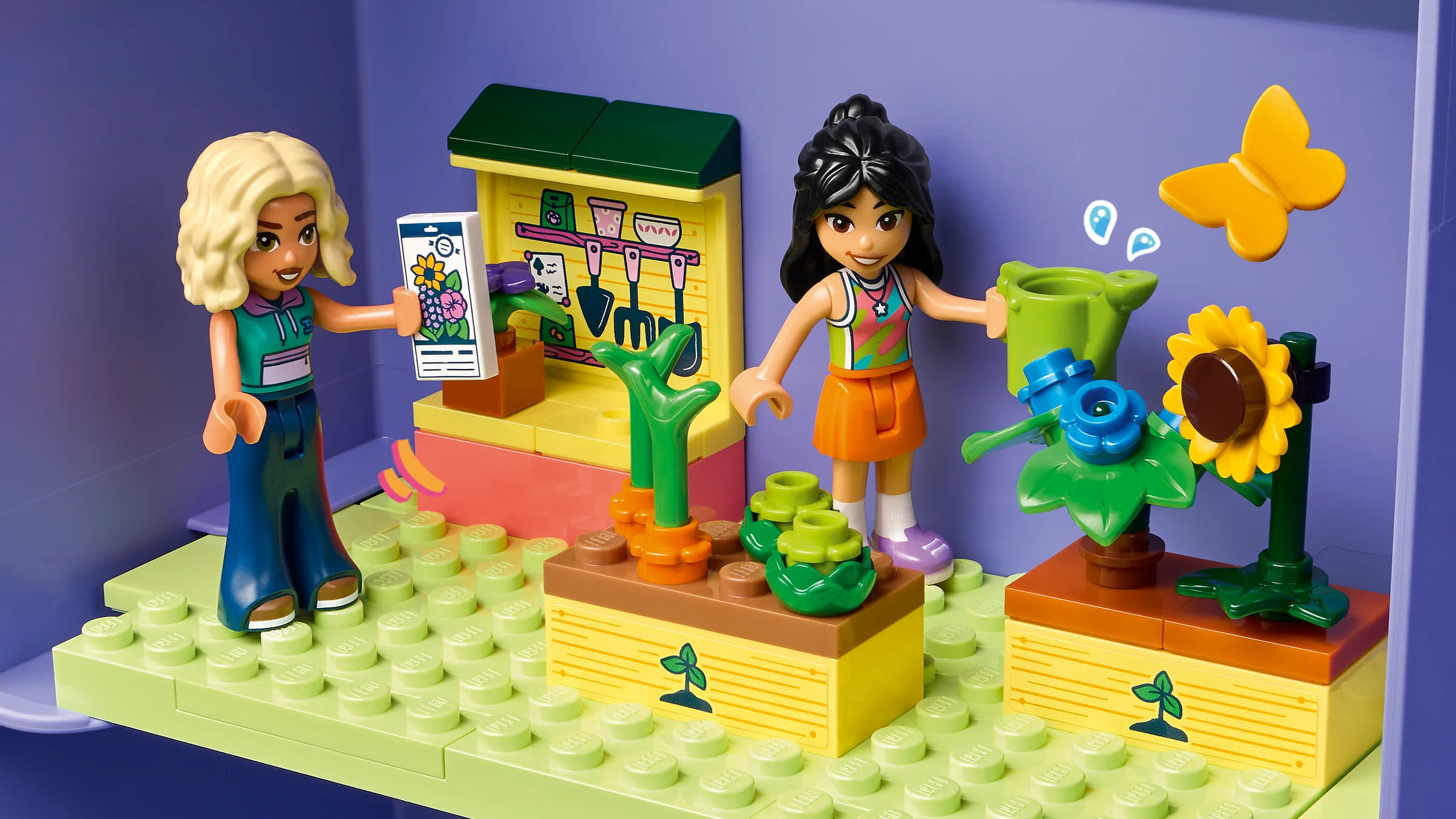 Scenă cu două figurine LEGO Friends într-o grădină colorată dintr-o căsuță de păpuși.
